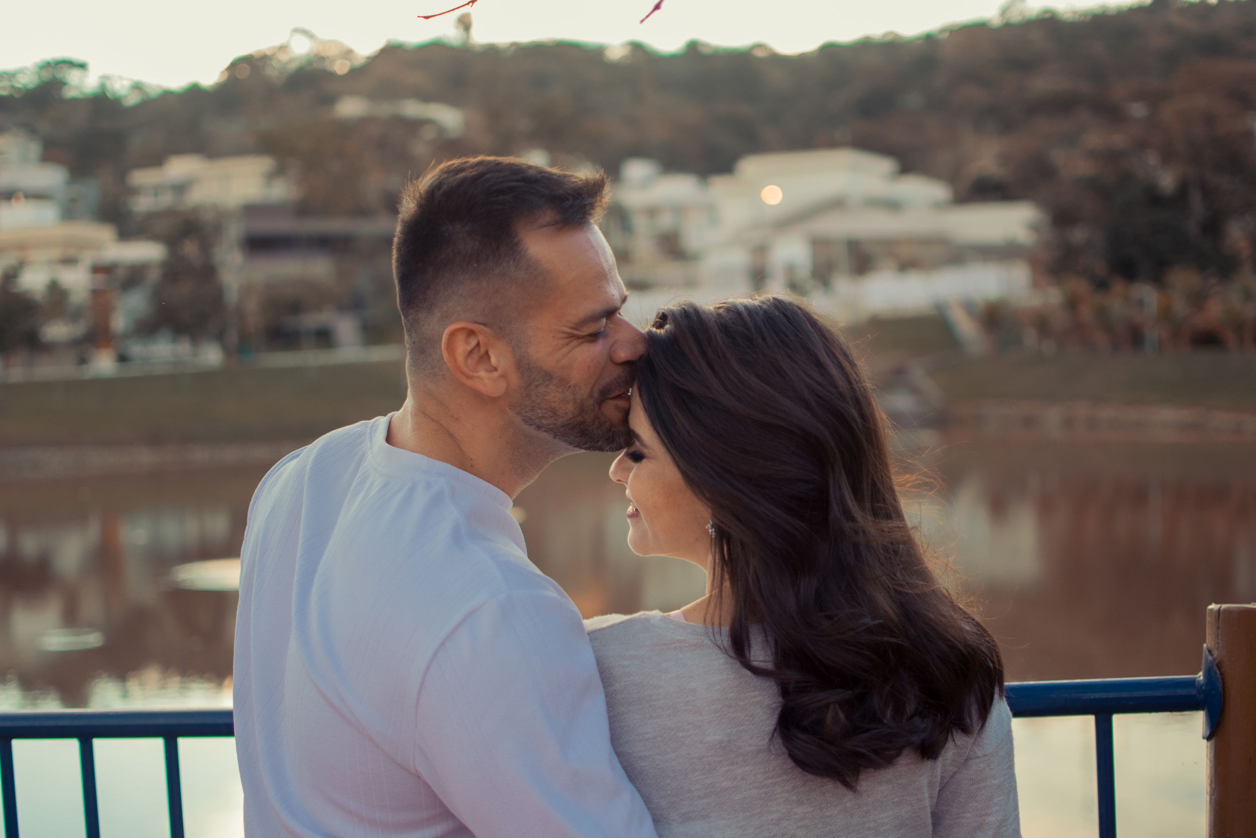 Two people embracing during golden hour against waterfront backdrop.