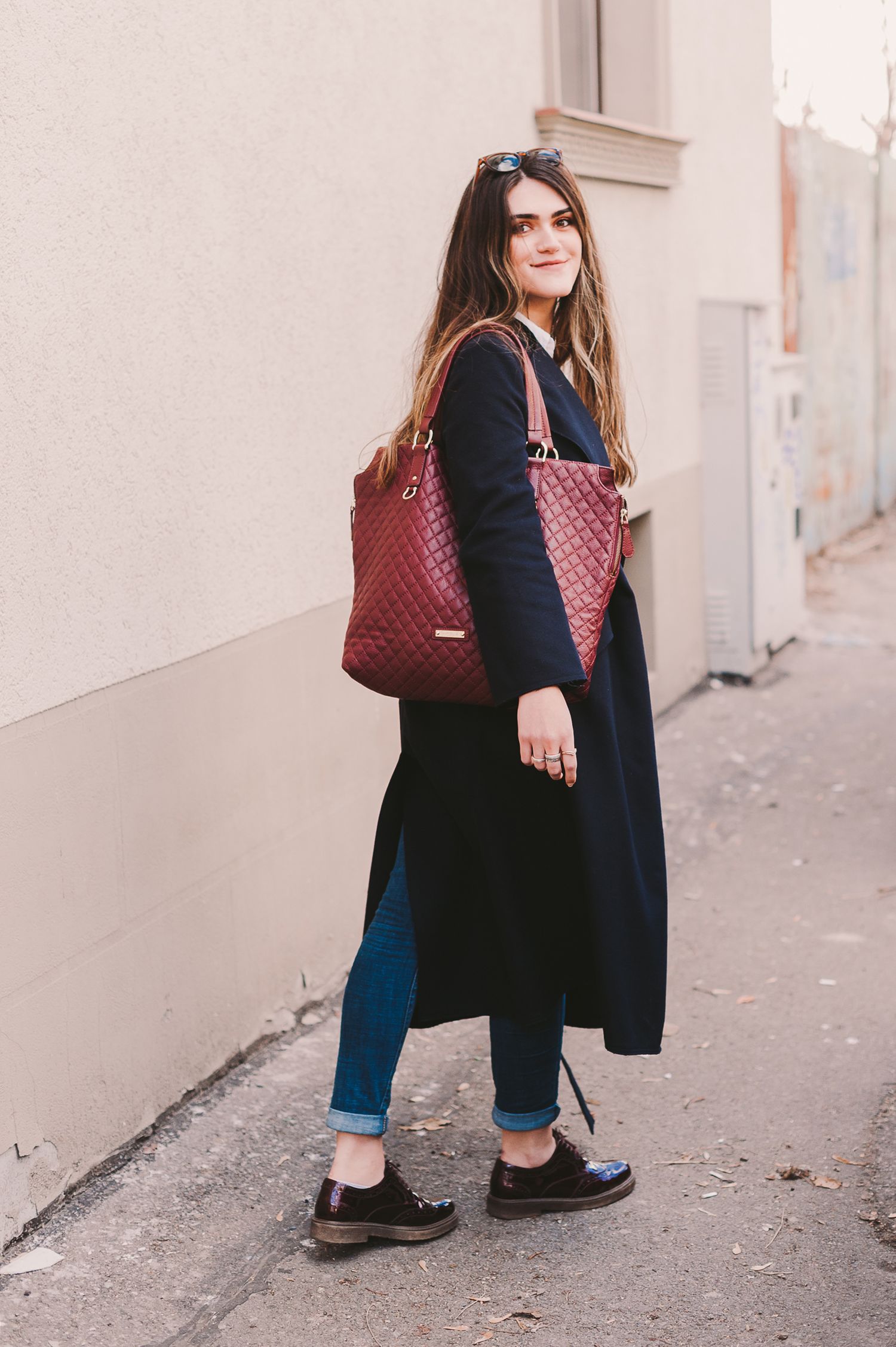 Street style photos featuring casual outfit with black coat, jeans and burgundy accessories.