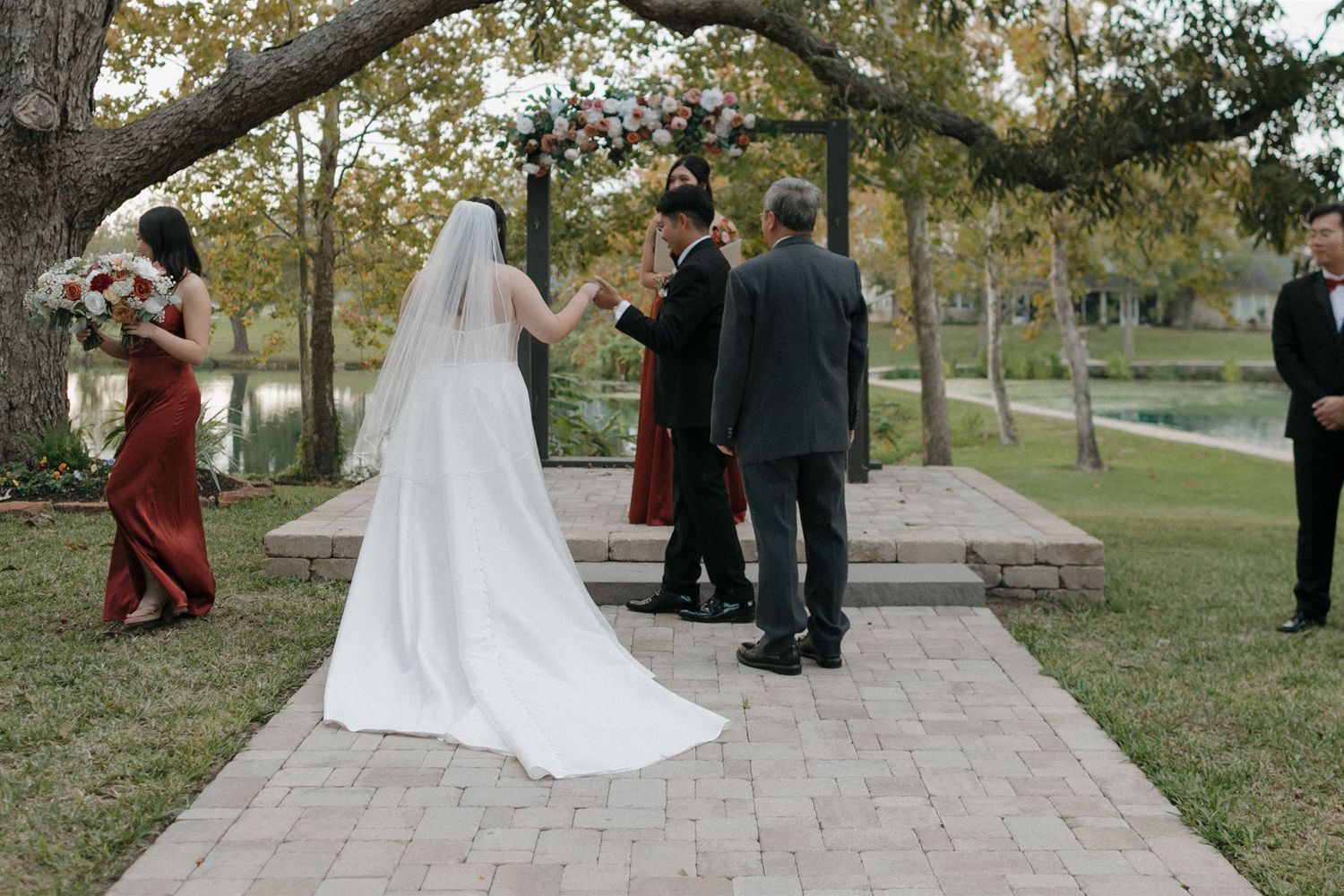 The exchange of vows during an outdoor wedding ceremony under a canopy of trees.