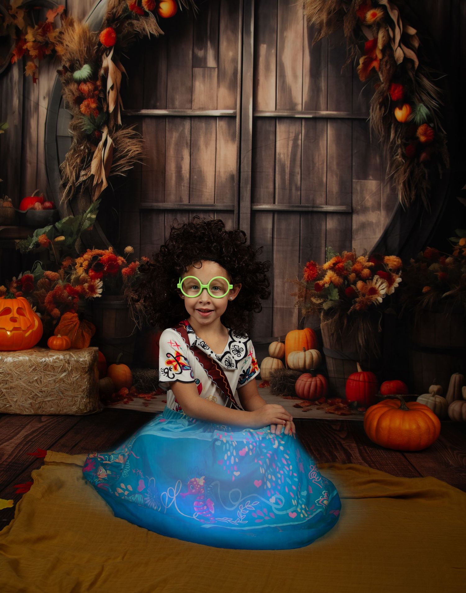 A joyful portrait in a blue skirt and glasses amid Halloween pumpkins and autumn decorations.