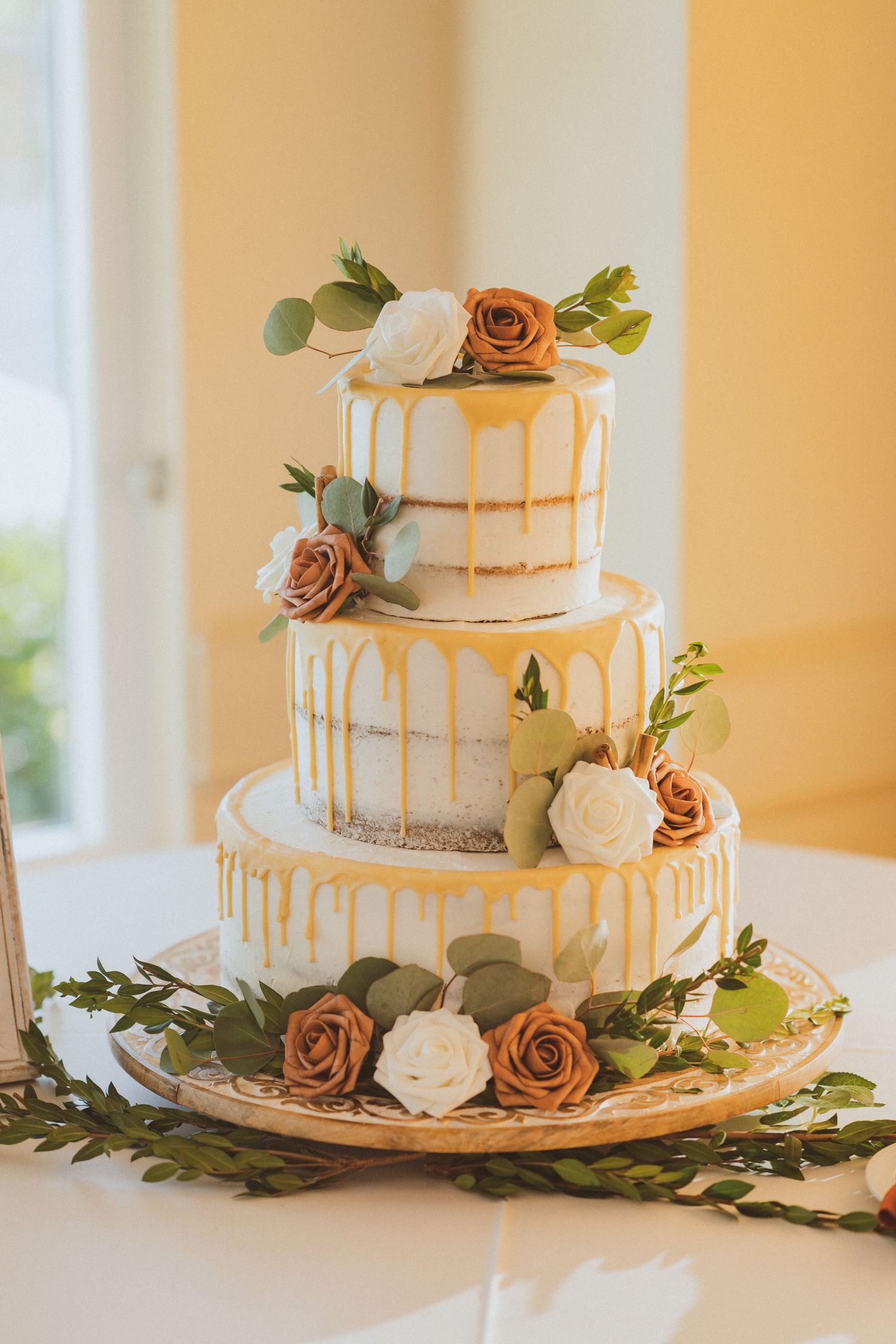 Elegant three-tier white wedding cake adorned with dusty rose and cream flowers.