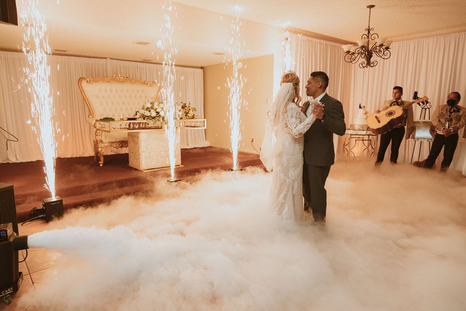 Couple dancing surrounded by fog effects and indoor sparklers at their wedding reception.