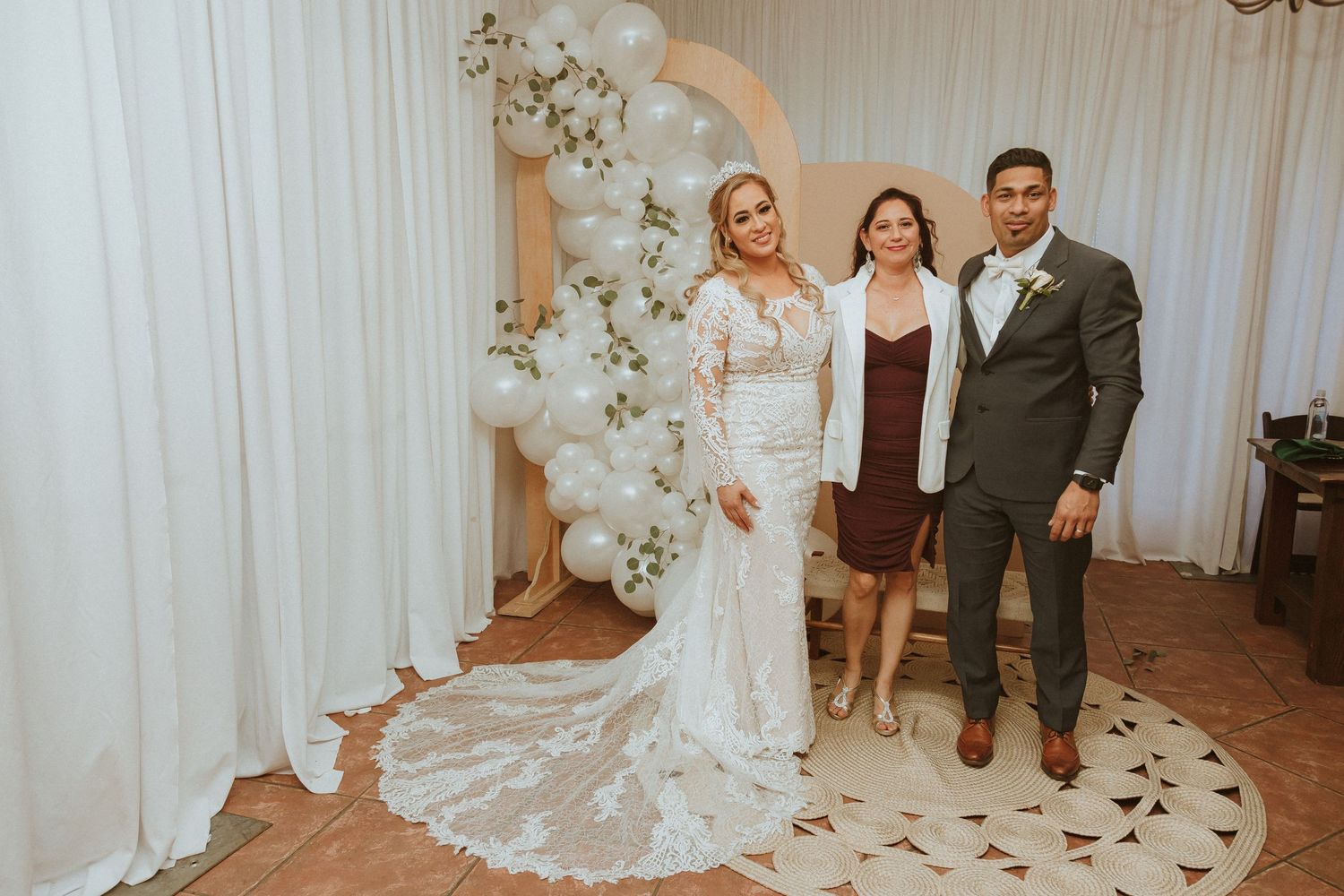 Wedding celebration with balloon arch decor and elegant white backdrop.