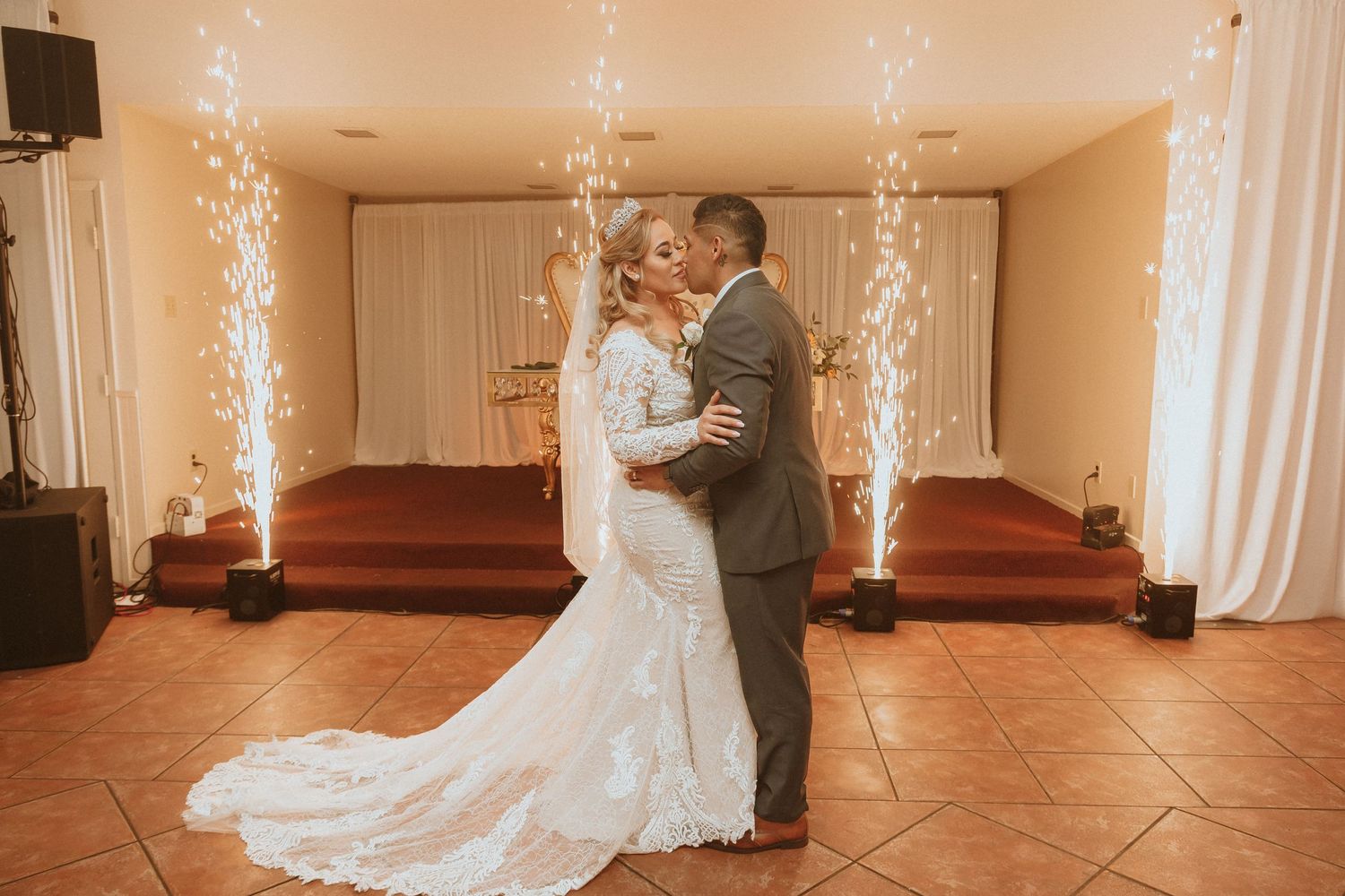 A romantic wedding photo of a couple embracing while sparkler fountains create a magical backdrop.