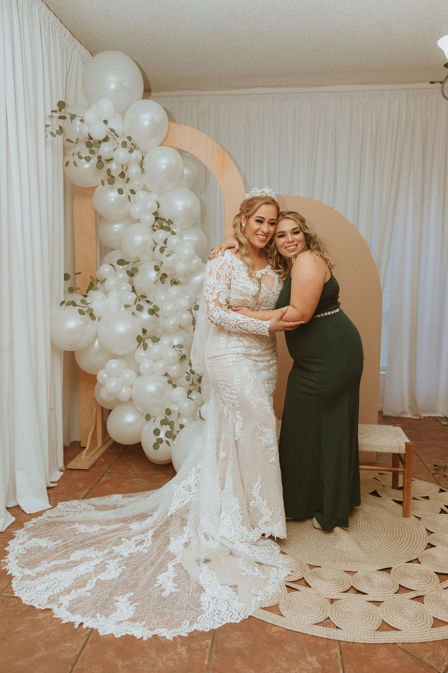 Wedding portrait showcasing intricate lace gown with long train against white balloon display.