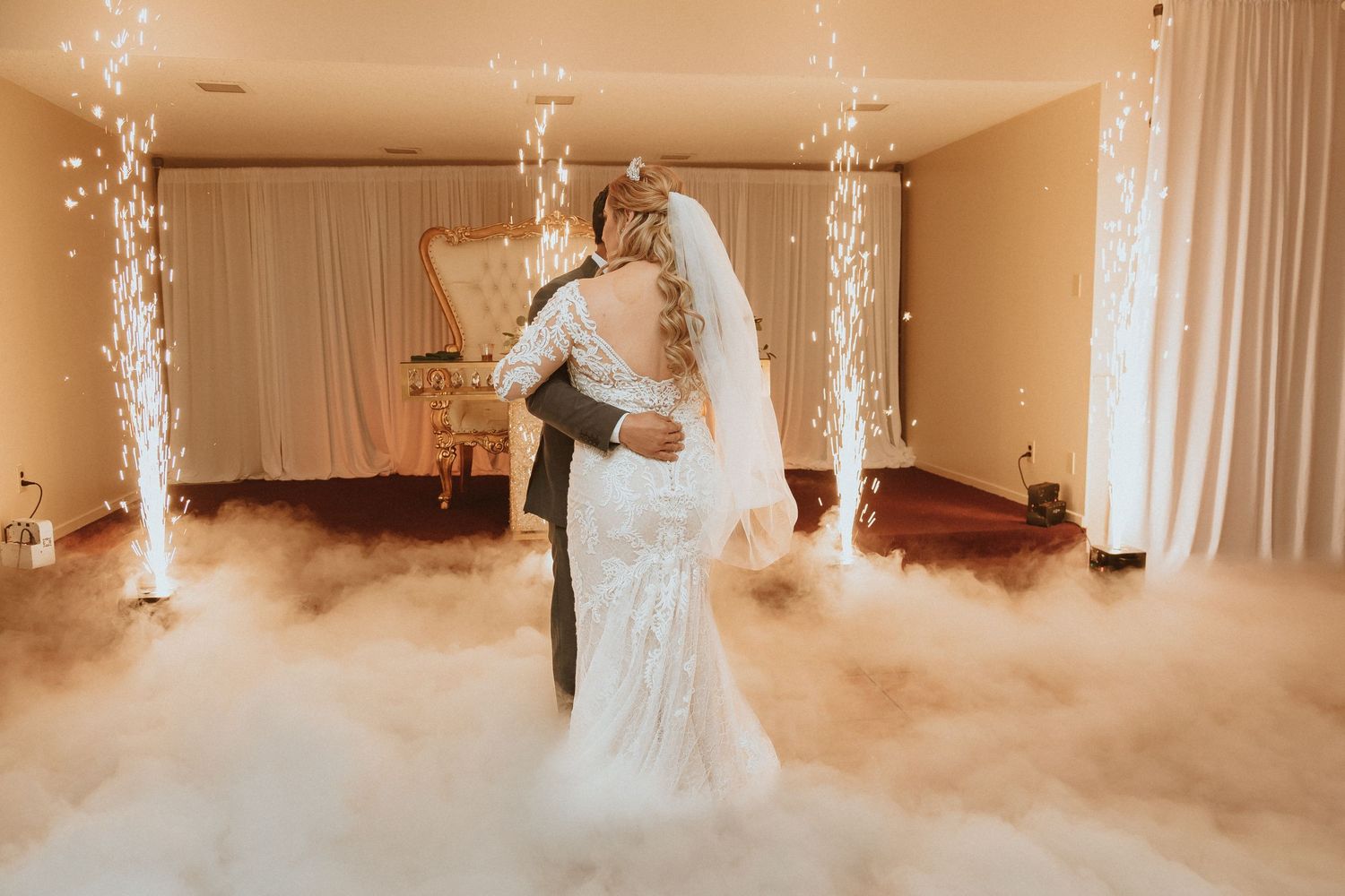 Wedding couple embraces during romantic dance surrounded by ethereal fog and sparkling effects.