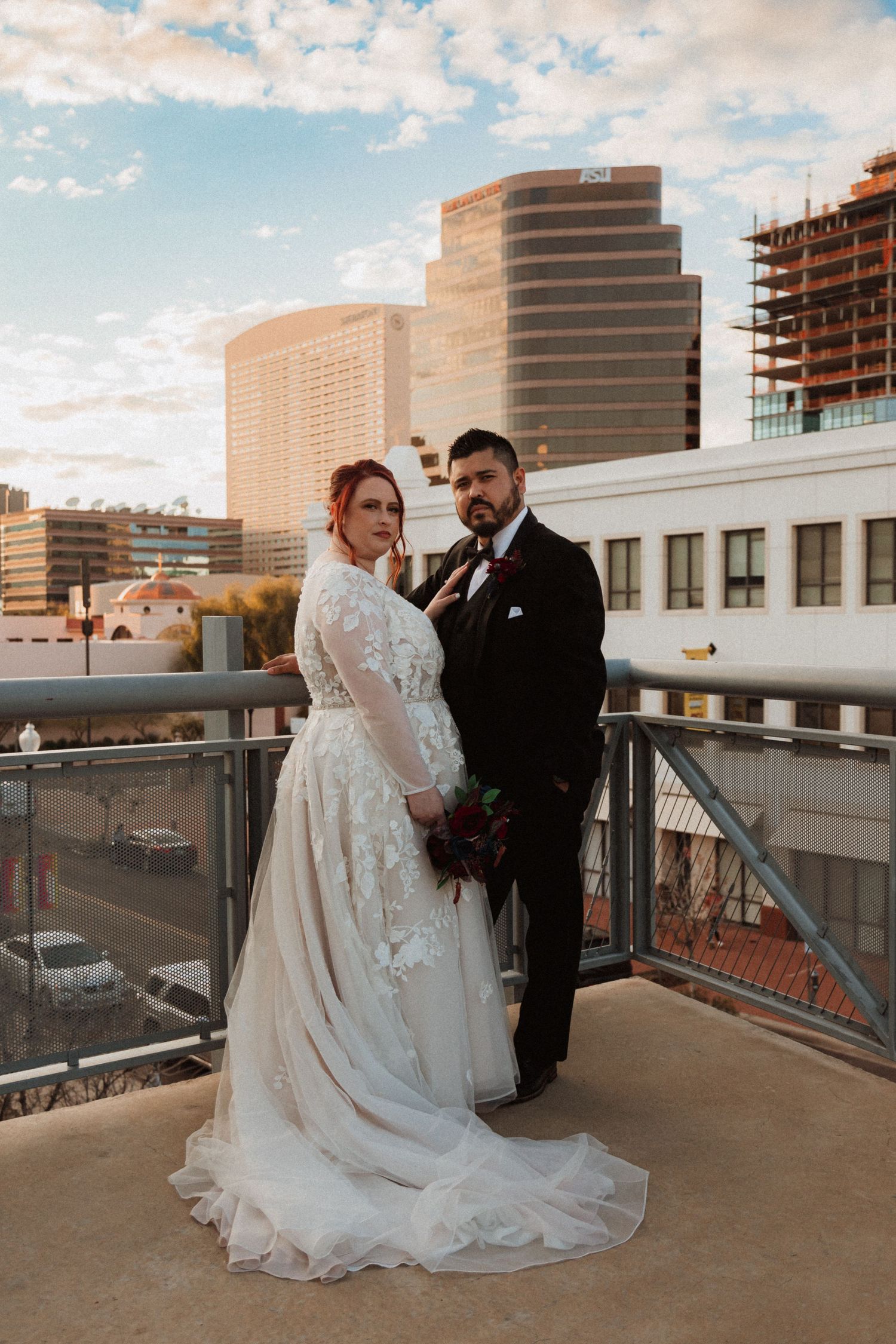 A sunset wedding portrait on an urban rooftop with modern architecture and construction in the background.