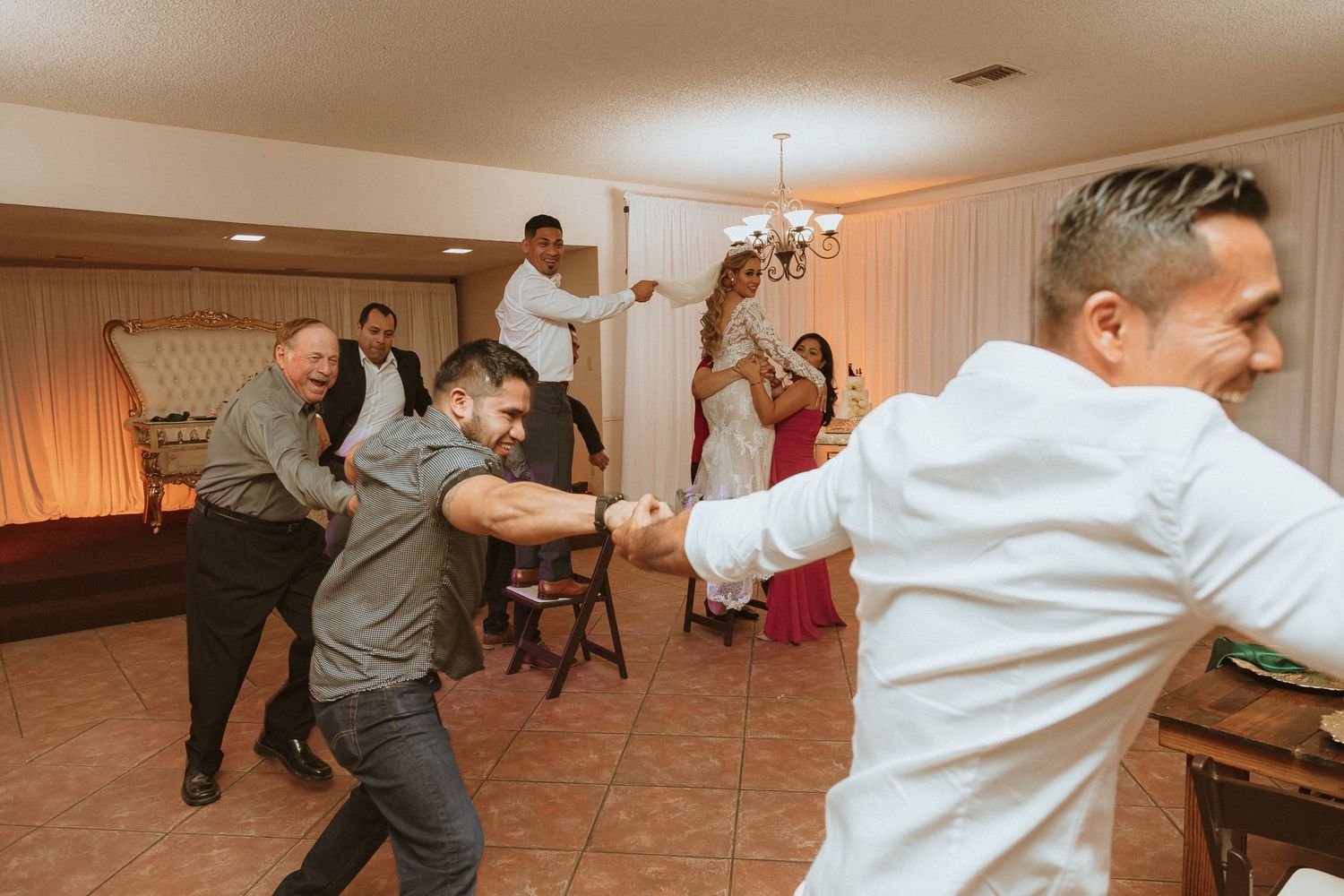 Celebration attendees performing synchronized dance moves in an indoor reception space.