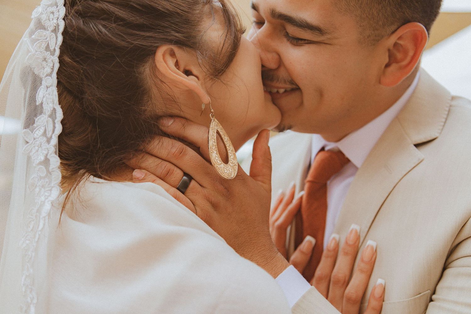 A tender wedding moment captured in warm tones as a couple shares their first kiss as newlyweds.