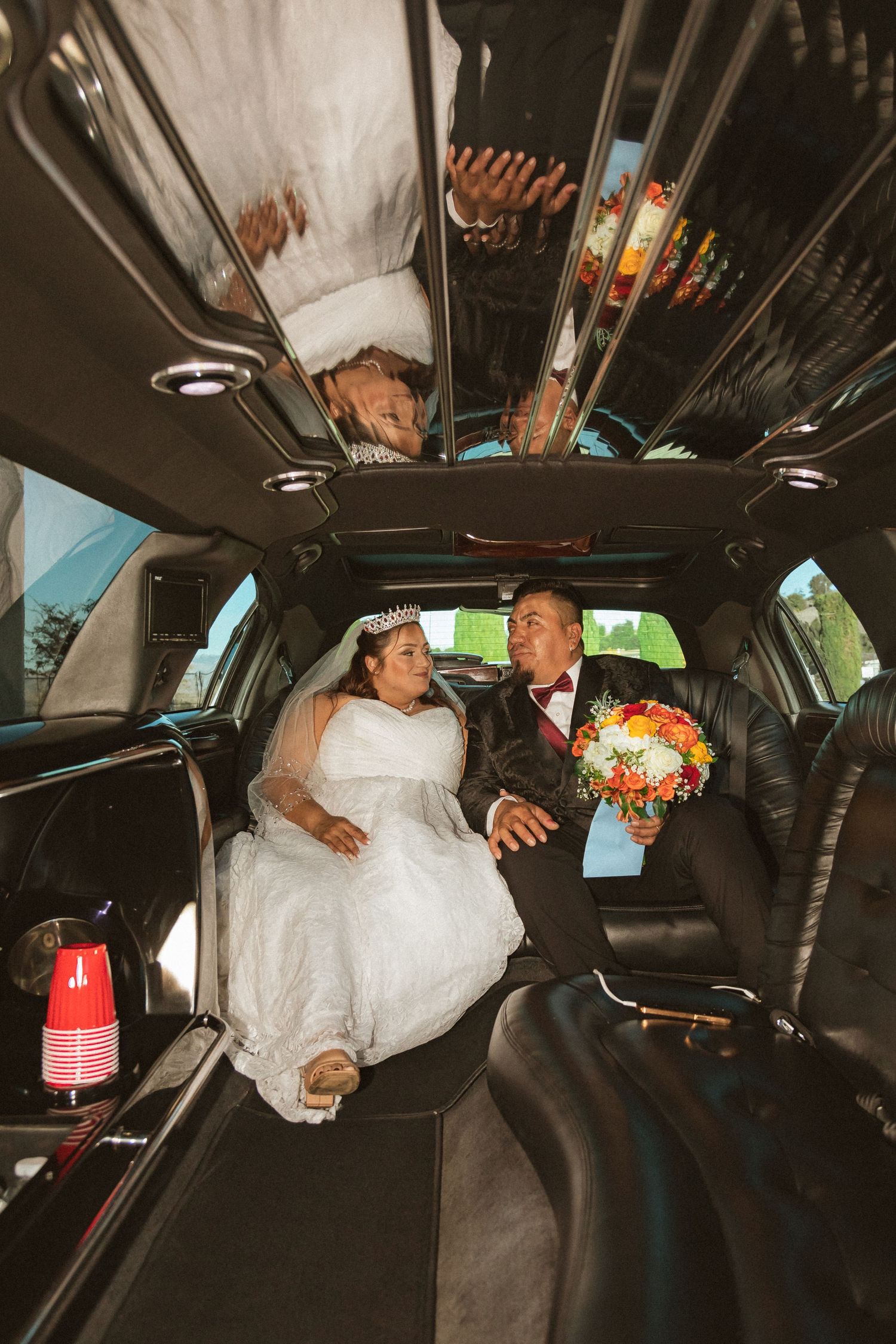 A couple shares a romantic moment in a wedding limousine interior with a colorful bouquet.