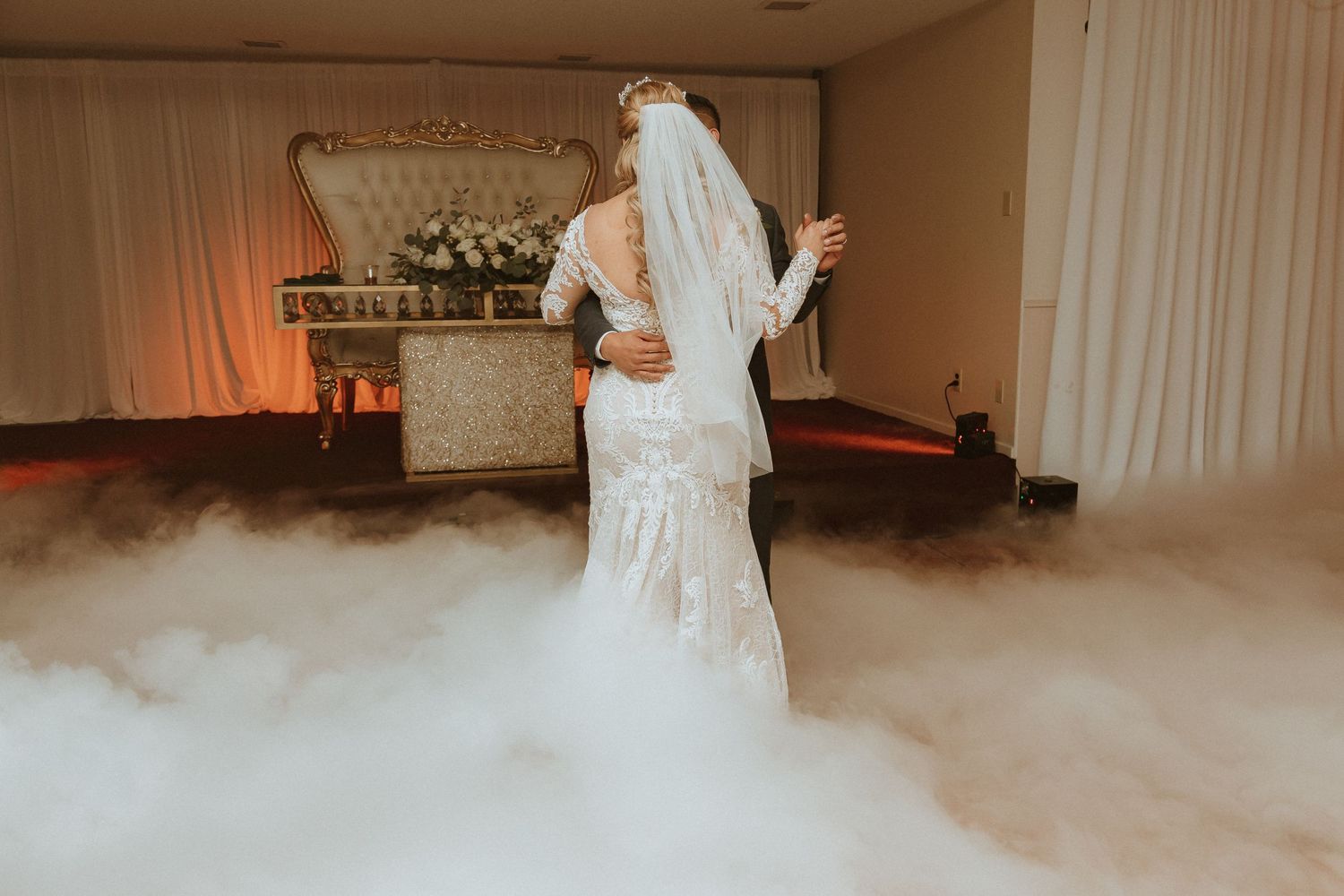 Lace wedding gown detail shown through atmospheric fog during romantic dance moment.