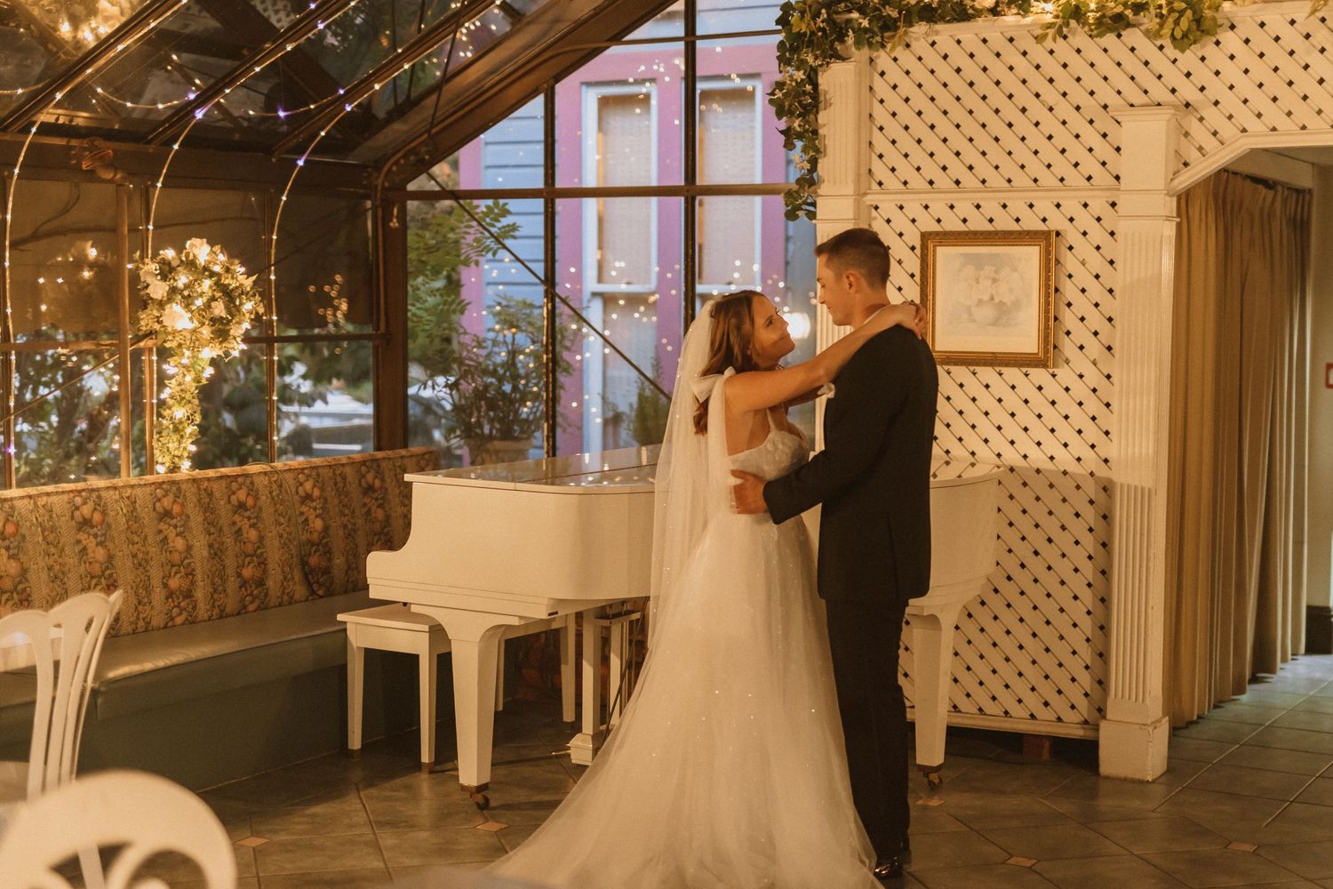Romantic dance moment under warm lighting with white piano and lattice wall decor.