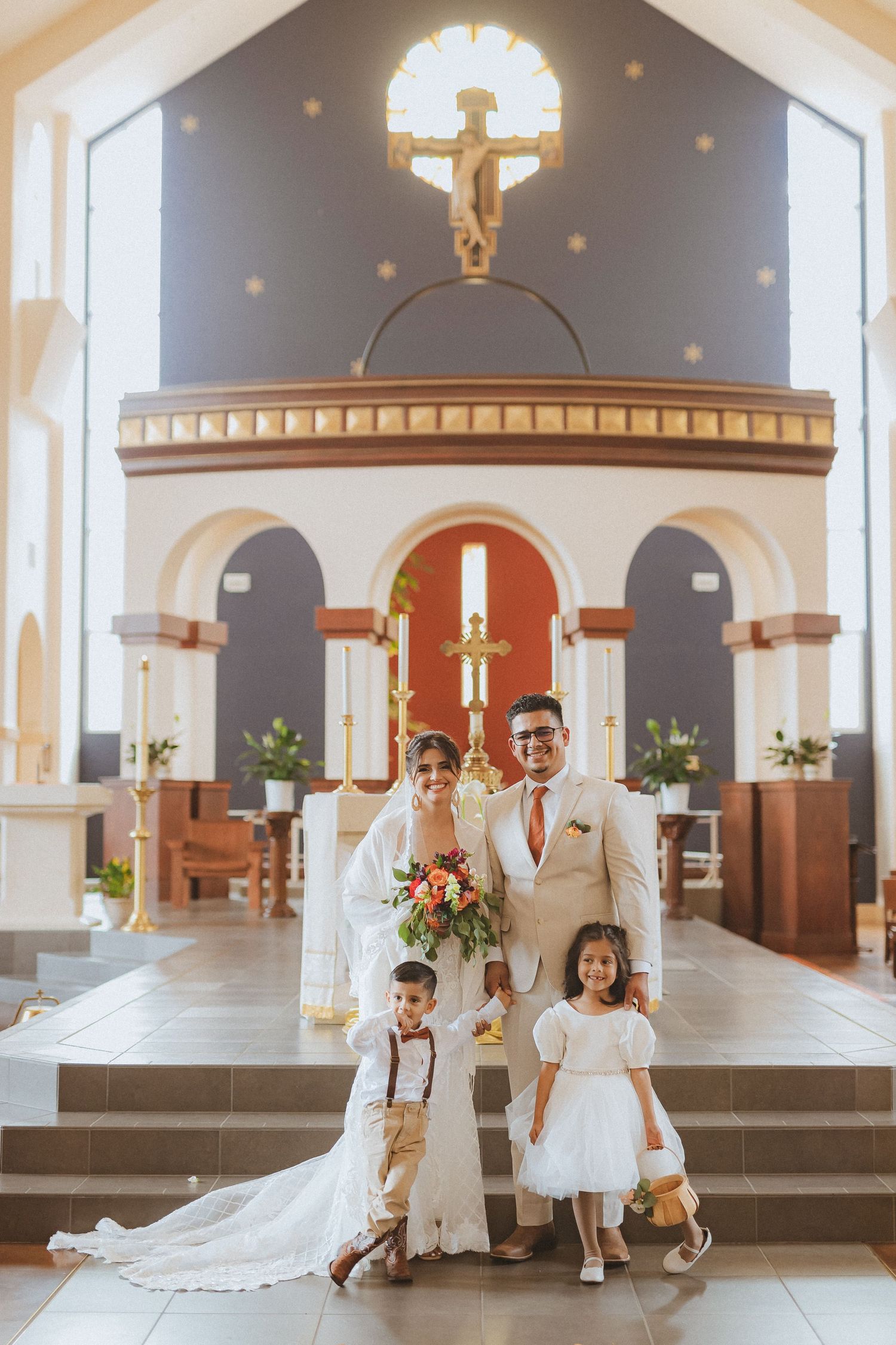 A wedding party poses at the altar with two children in formal attire.