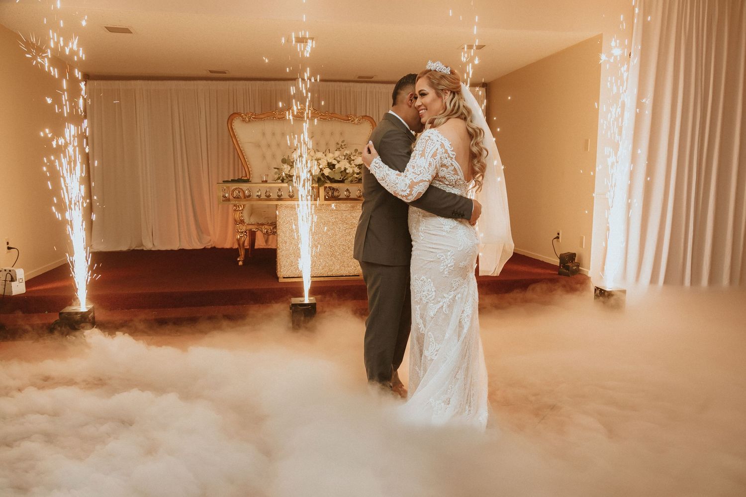 A beautiful wedding dance captured in warm tones with fog effects and sparkling fountains creating ambiance.