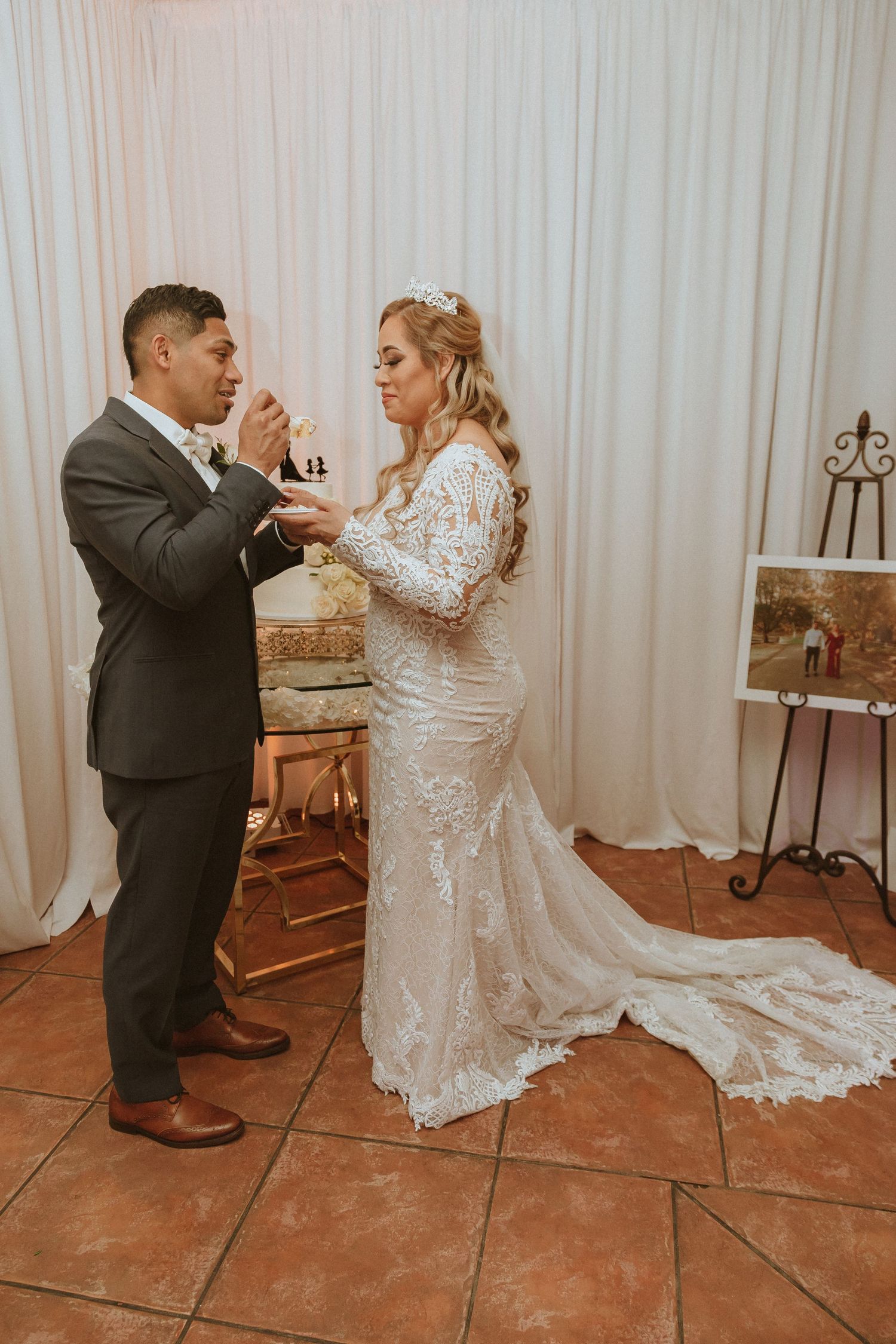 Newlyweds sharing wedding cake in a traditional cake-feeding moment.