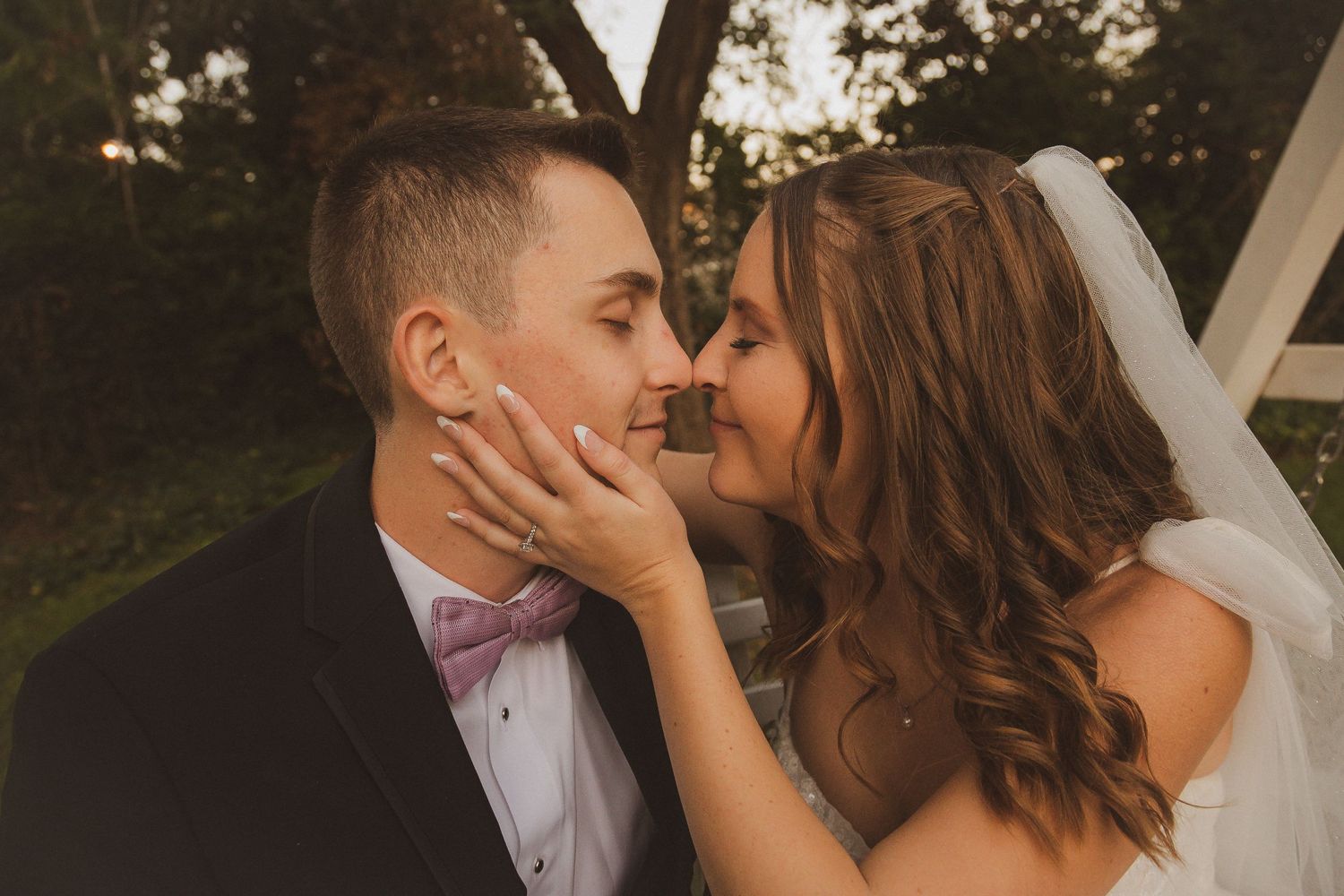 Intimate sunset wedding portrait with couple sharing tender moment outdoors.