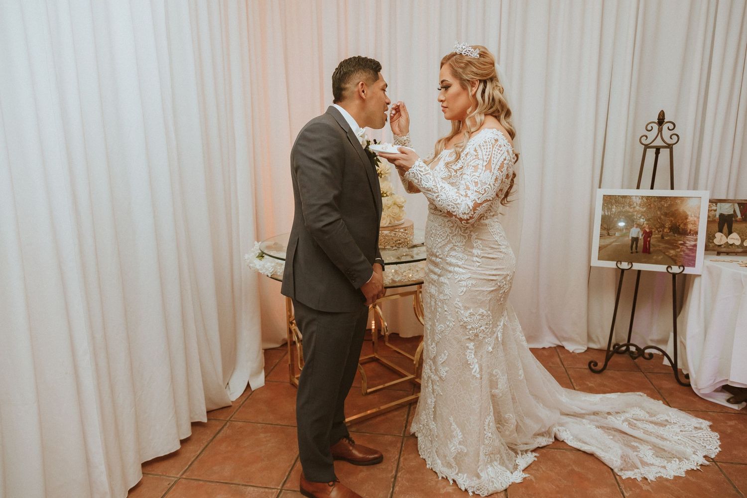Playful moment as newlyweds feed each other wedding cake during their reception celebration.
