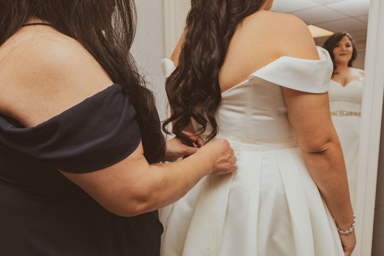 Close-up detail shot of dress adjustments during a wedding preparation moment.