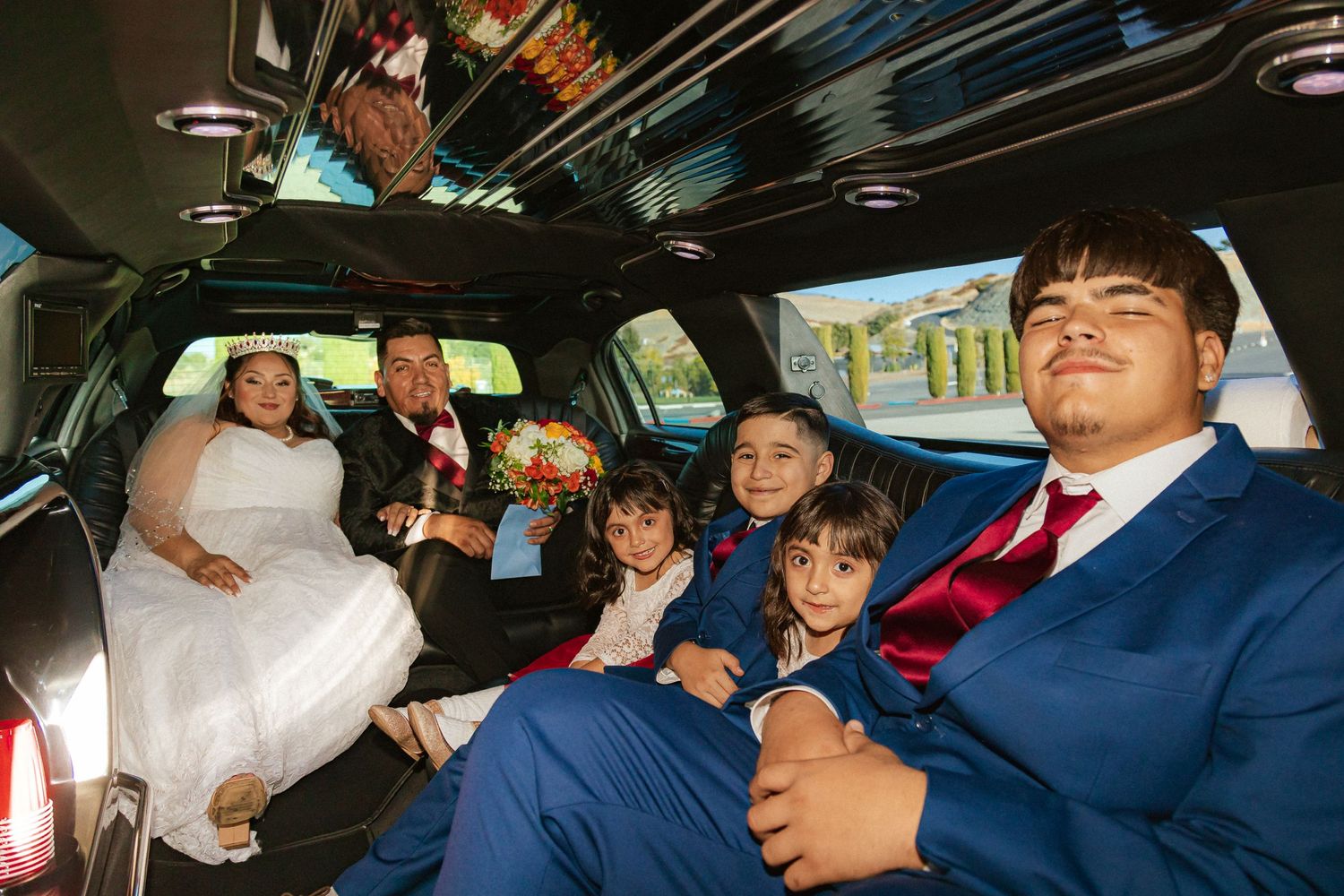 Wedding party enjoys a fun ride together in a spacious black limousine.
