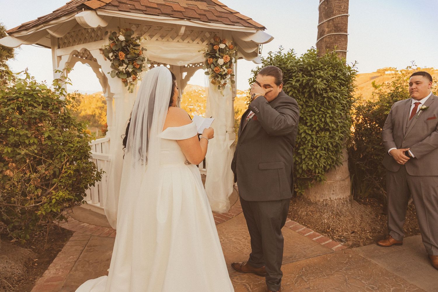 Emotional exchange of vows during outdoor sunset wedding ceremony.