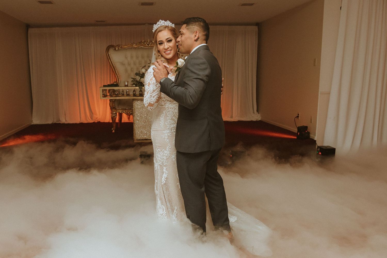Tender moment between newlyweds during their reception dance surrounded by fog effects.