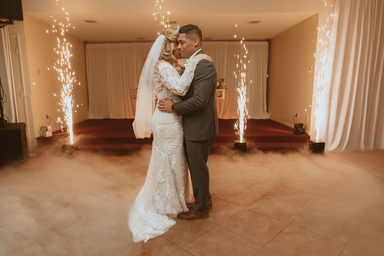Wedding dance in a beautifully lit reception hall with dramatic sparkler fountains and fog effects.