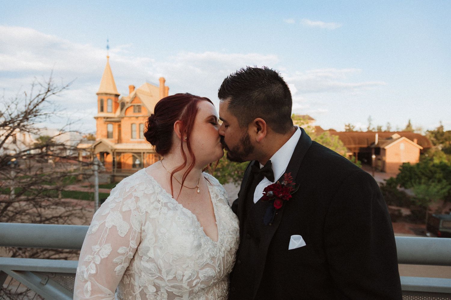 Romantic wedding moment captured with historic church spire in background during sunset.