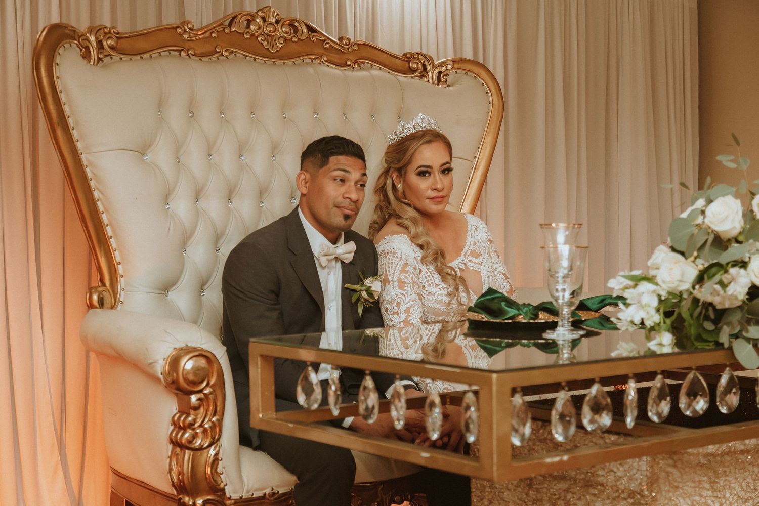 Newlyweds sharing an intimate moment at their reception sweetheart table with ornate gold frame backing.
