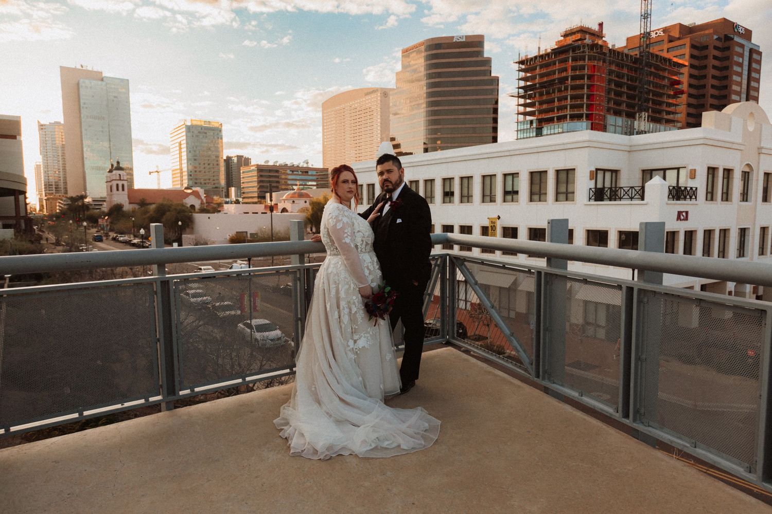 Wedding portrait against a cityscape backdrop during sunset on a rooftop terrace.