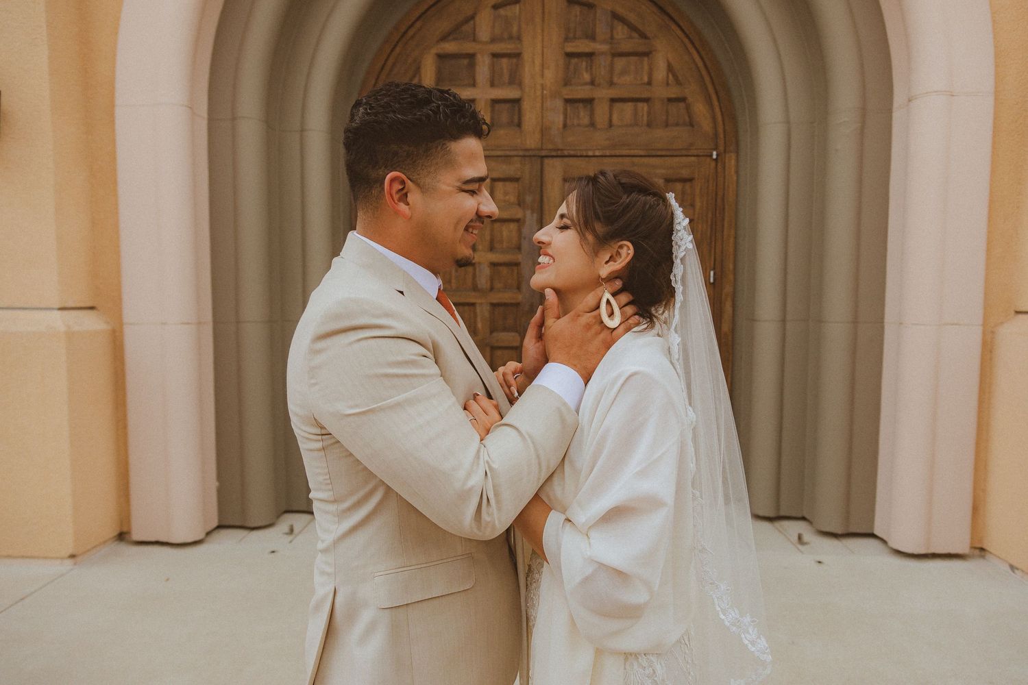 A tender moment between a couple in formal attire against an arched doorway.