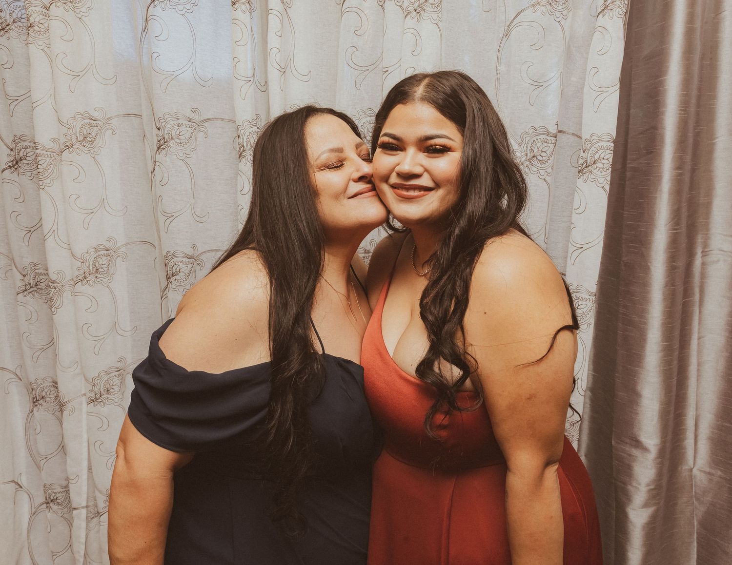 Close friends in formal attire share an affectionate moment during special occasion.