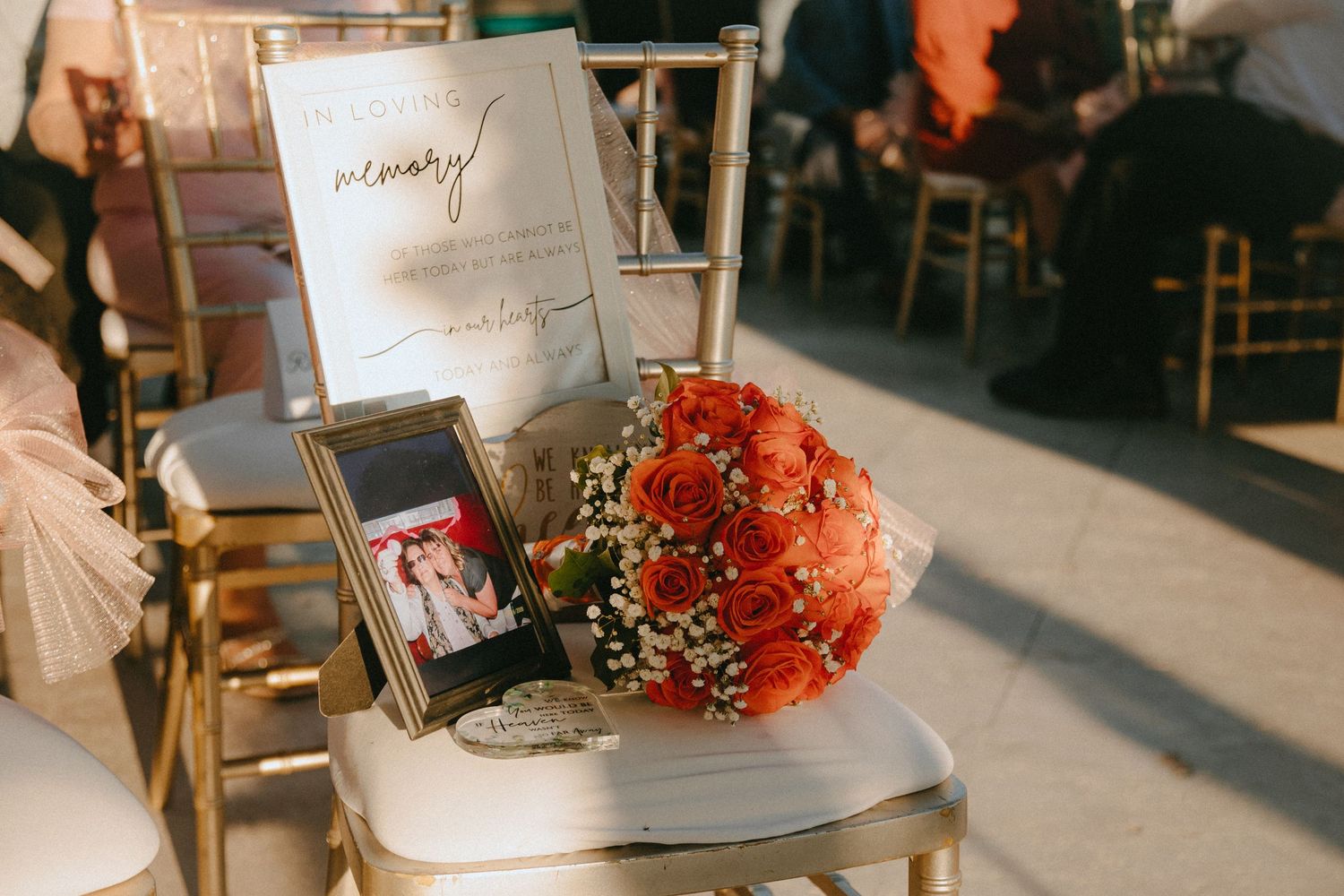 Wedding decor featuring coral rose bouquet, framed photo and welcome sign on gold chiavari chair.