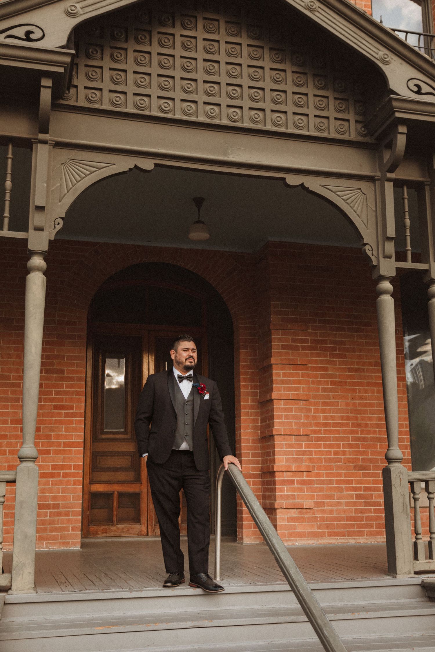A classic portrait under the detailed archway of a Victorian mansion's front porch.