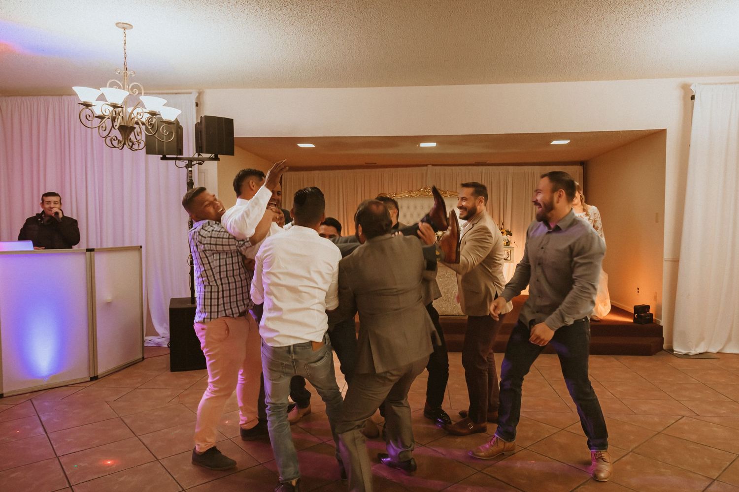 People gather in a circle on the dance floor during a wedding reception.