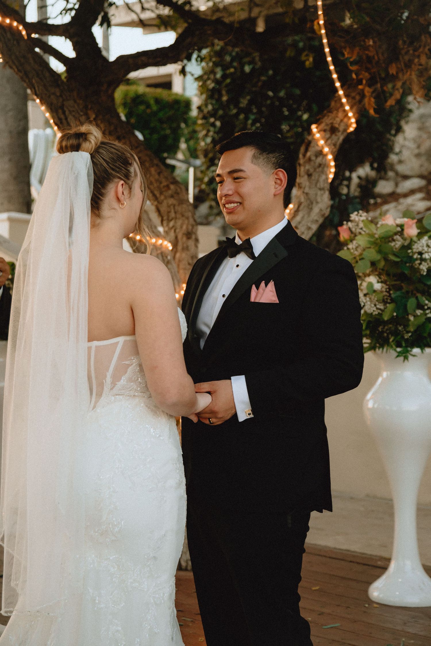 Couple holds hands and smiles during intimate outdoor wedding ceremony.