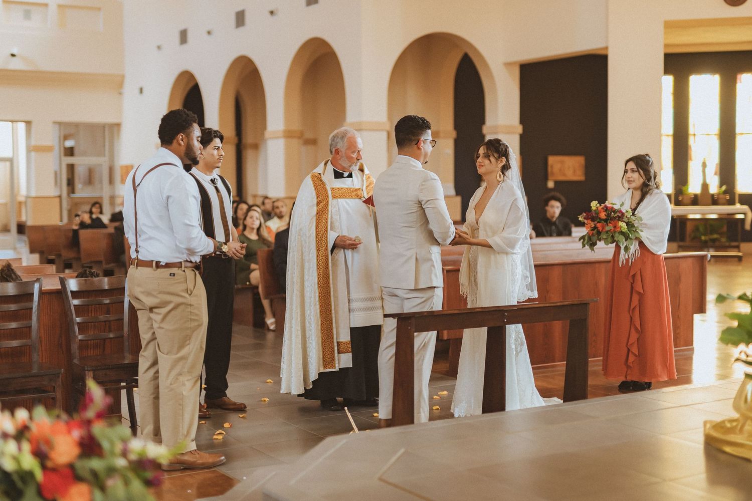 A small group stands near the altar during a church ceremony with warm lighting.