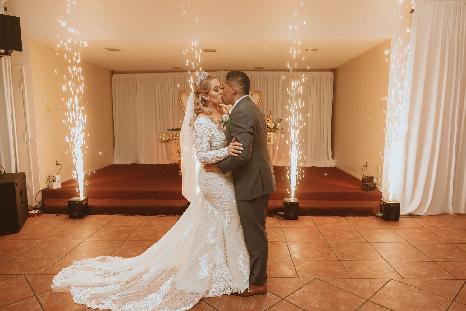 An intimate wedding dance moment with sparklers and white draping creating a romantic atmosphere.