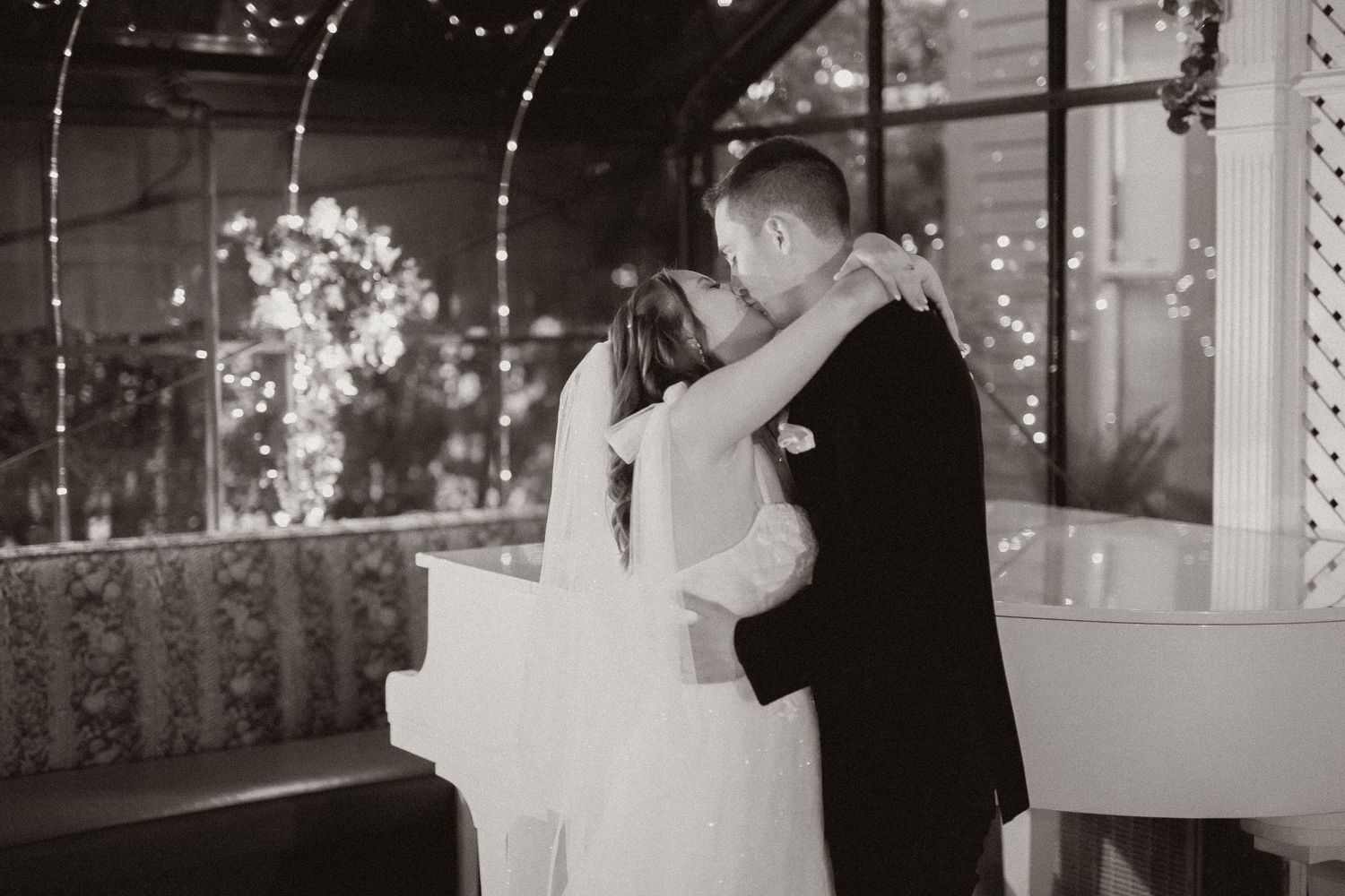 Intimate black and white moment captured between newlyweds under sparkling lights and floral decor.