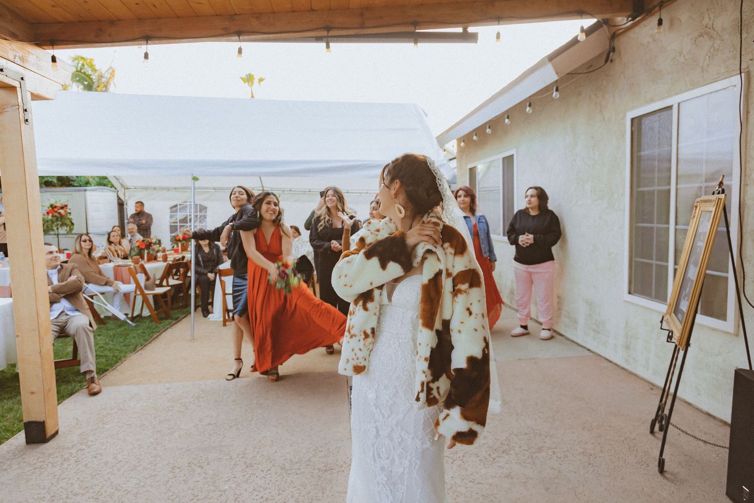 A joyful bride tosses her wedding bouquet while guests watch in anticipation.