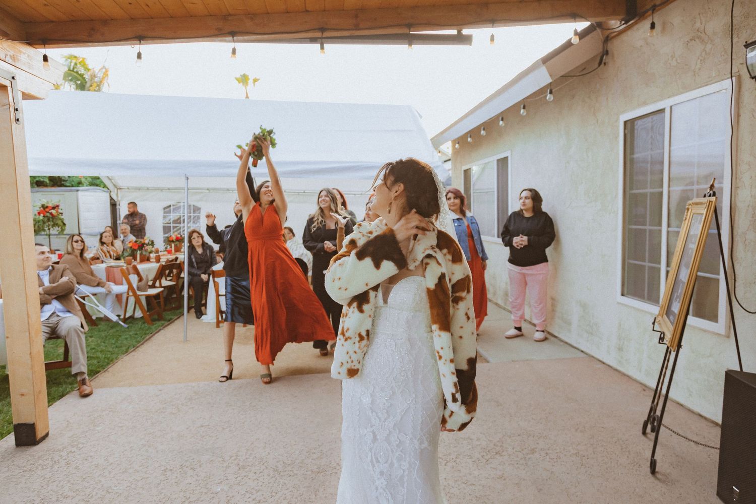 A bride in white lace celebrates during the wedding bouquet toss tradition.