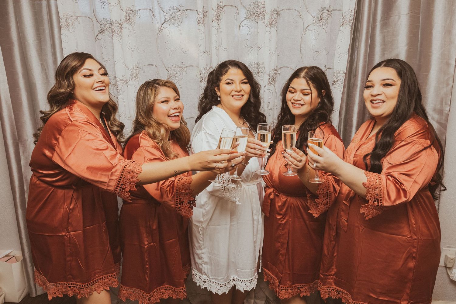 Bridal party celebrates with a champagne toast in matching satin robes.