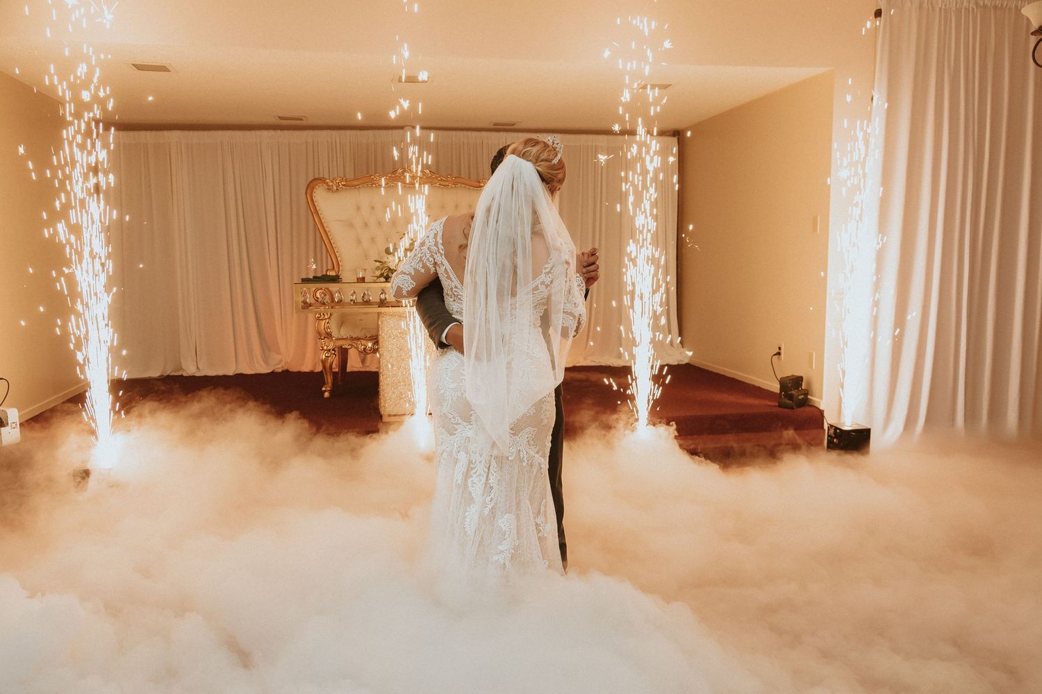 Dramatic silhouette of wedding dance framed by sparkling fountains and rolling fog effects.