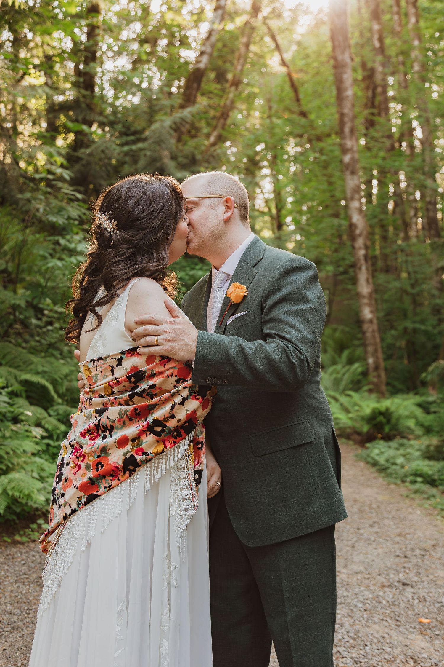 A tender moment between newlyweds on a sunlit forest path.