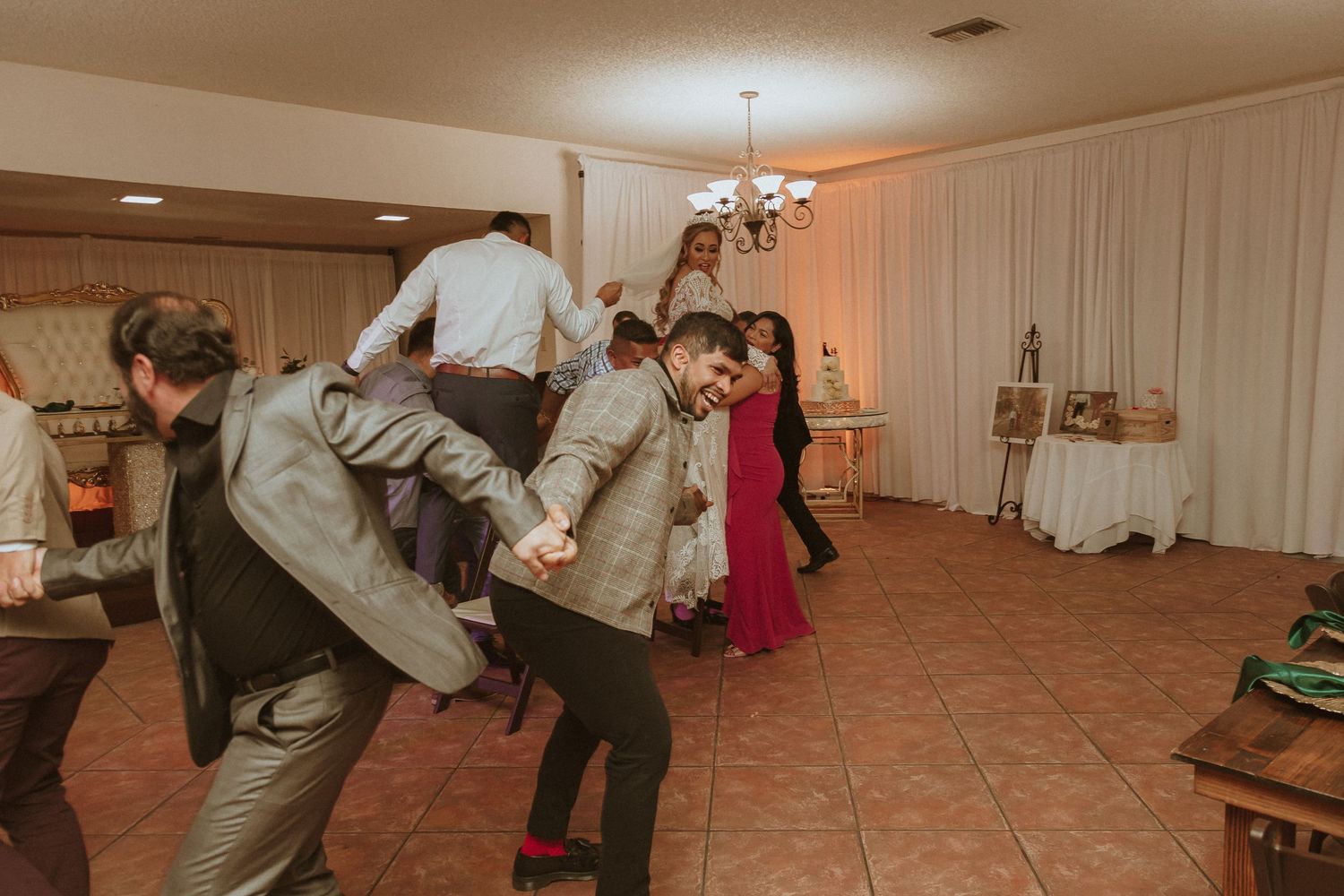 Dancers performing coordinated moves at an indoor party with white draped walls.