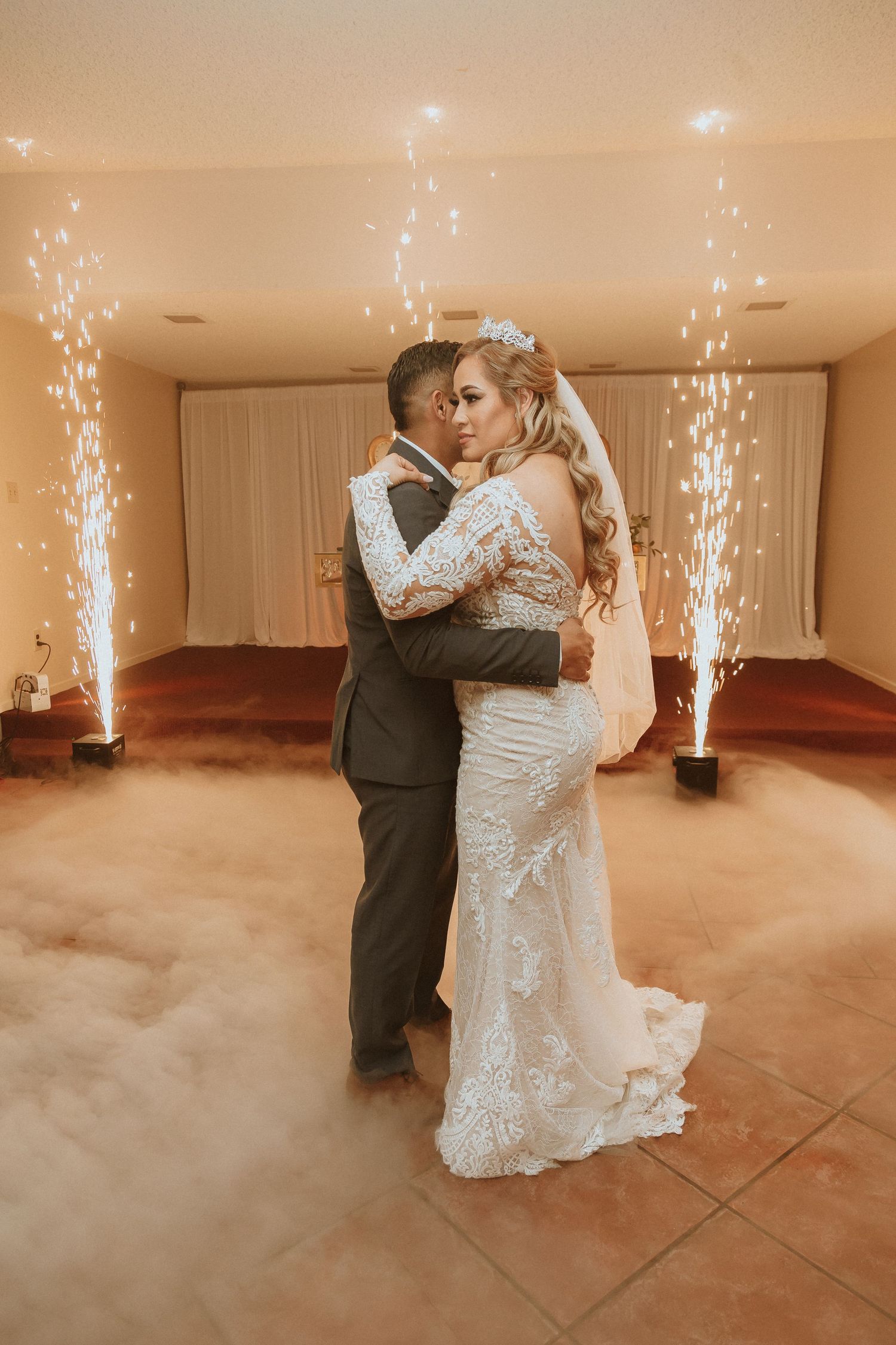 Romantic wedding dance captured in warm tones with sparkler fountains and low-lying fog effects.