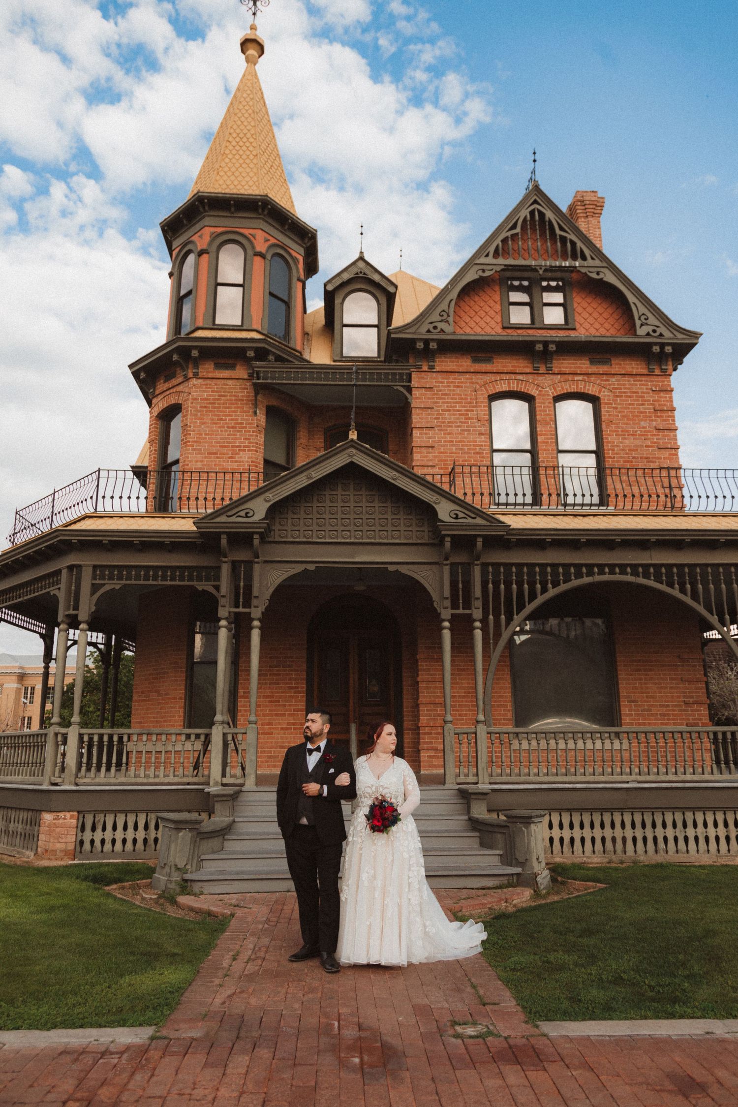 A wedding ceremony at a Victorian-style brick mansion with ornate architectural details and a conical tower.