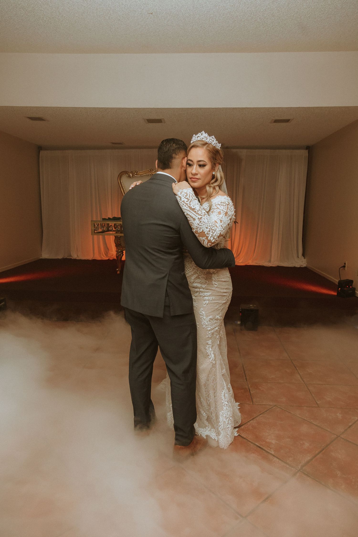 A wedding couple shares an intimate dance moment surrounded by atmospheric fog effects.