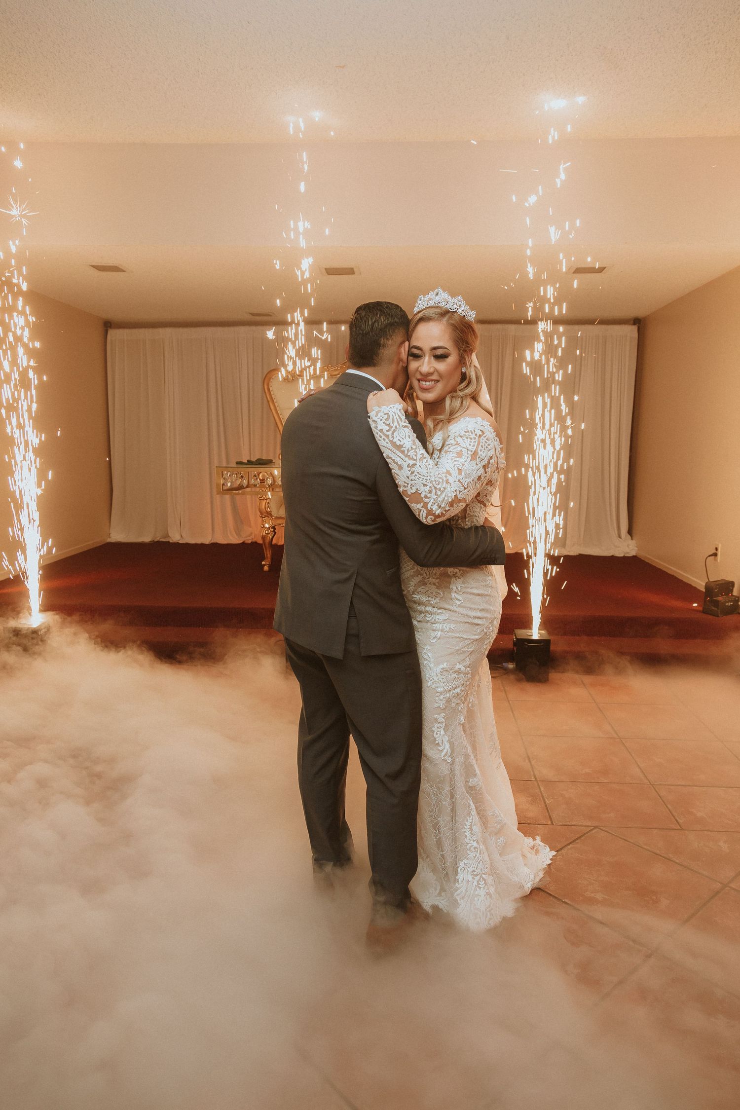 A wedding couple dances amid indoor sparklers and dramatic fog effects creating a magical atmosphere.