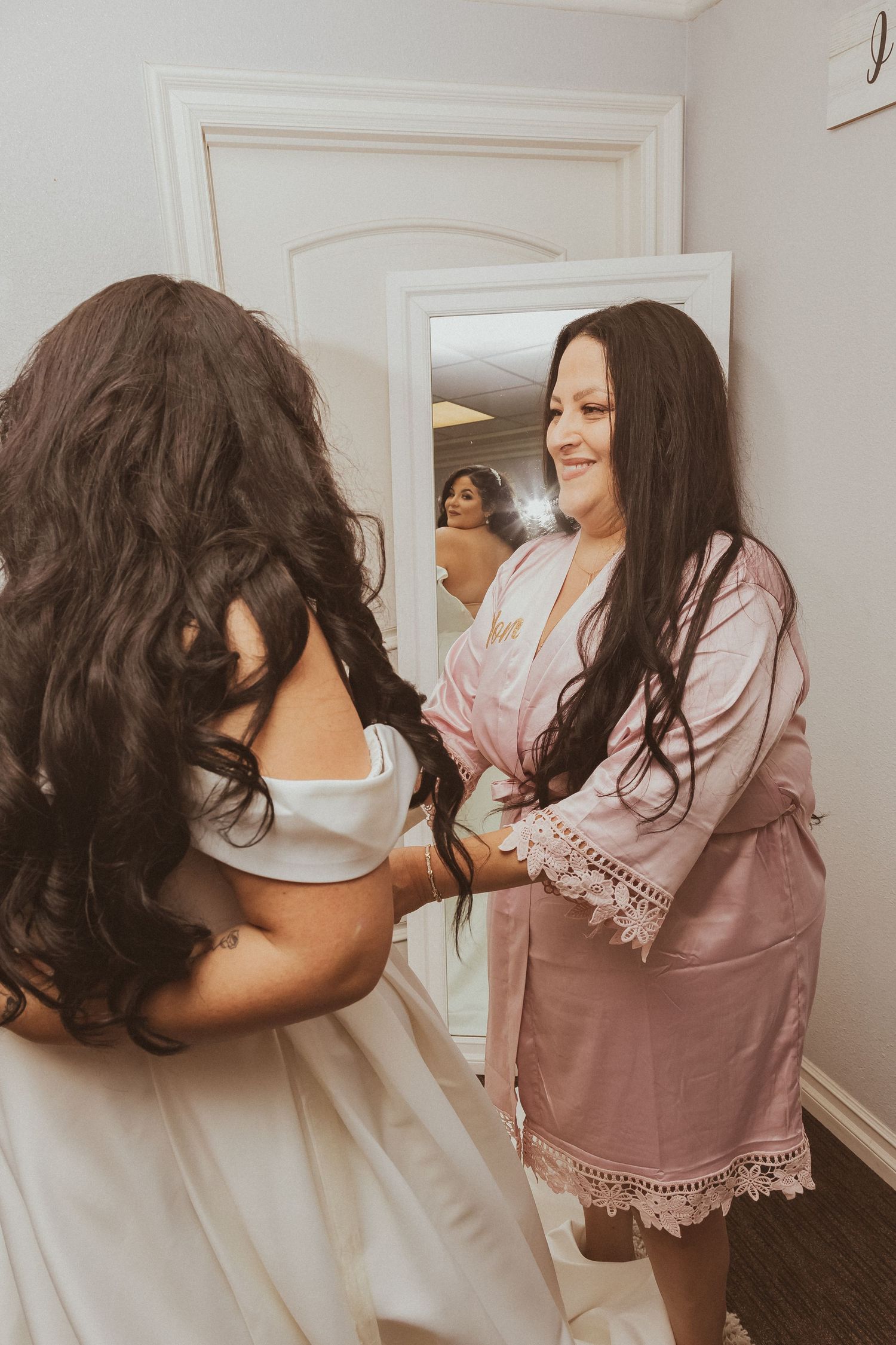 Getting ready scene with wedding dress preparations in cream-colored room.