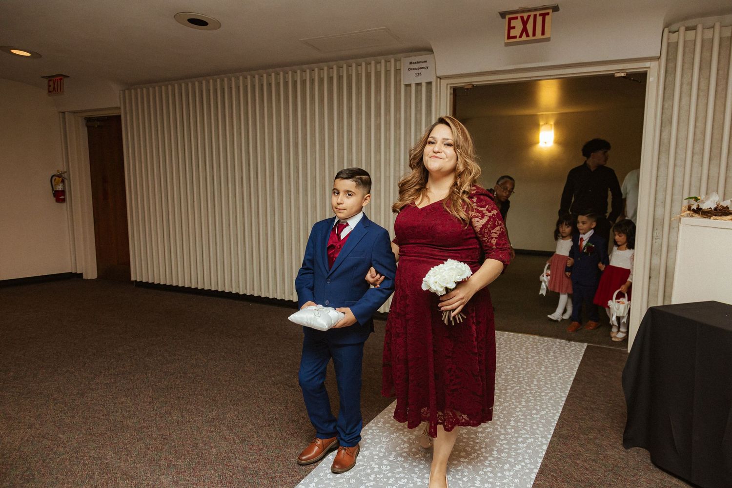 Reception processional with attendants in formal burgundy and navy attire.